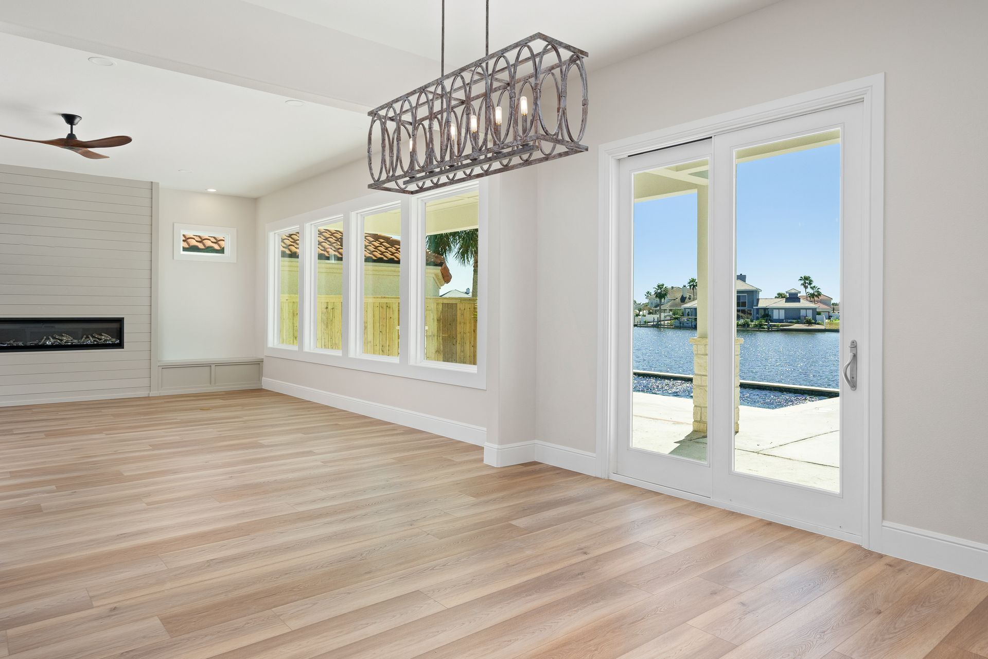 An empty living room with hardwood floors and a chandelier
