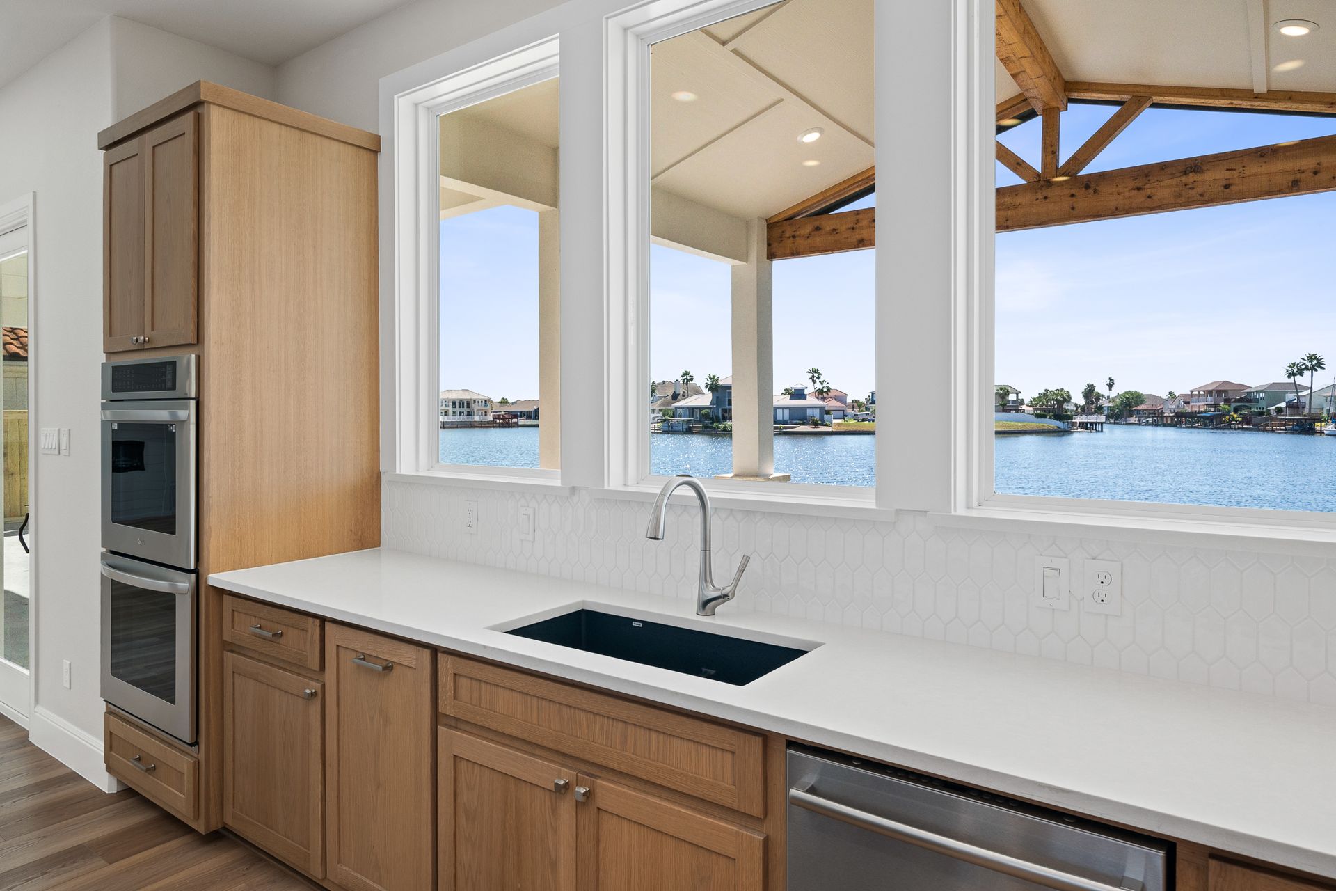 A kitchen with wooden cabinets , stainless steel appliances , a sink , and a view of the water.