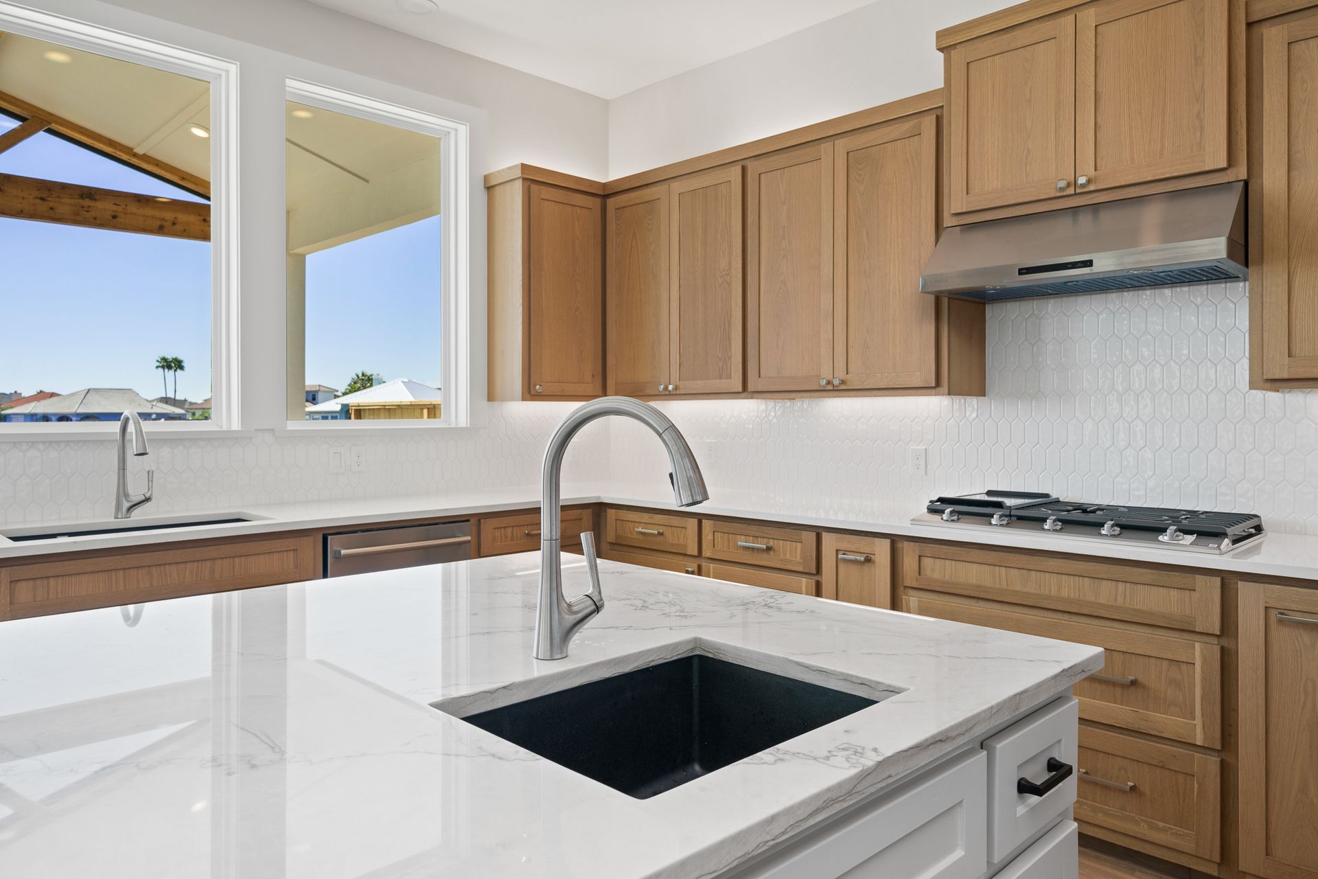 A kitchen with wooden cabinets , white counter tops , a sink and a stove.