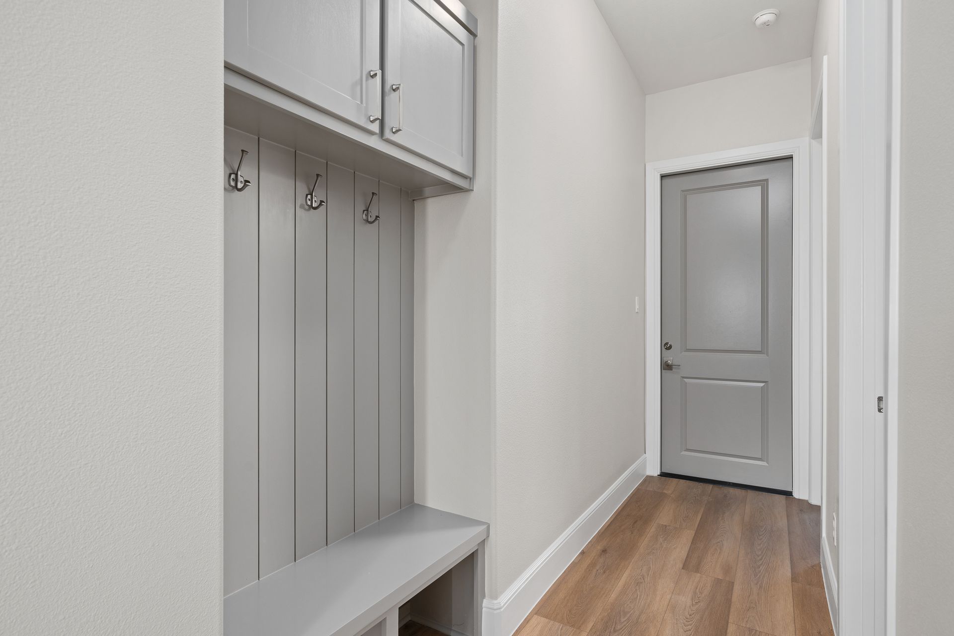 A hallway with a gray door and a bench.