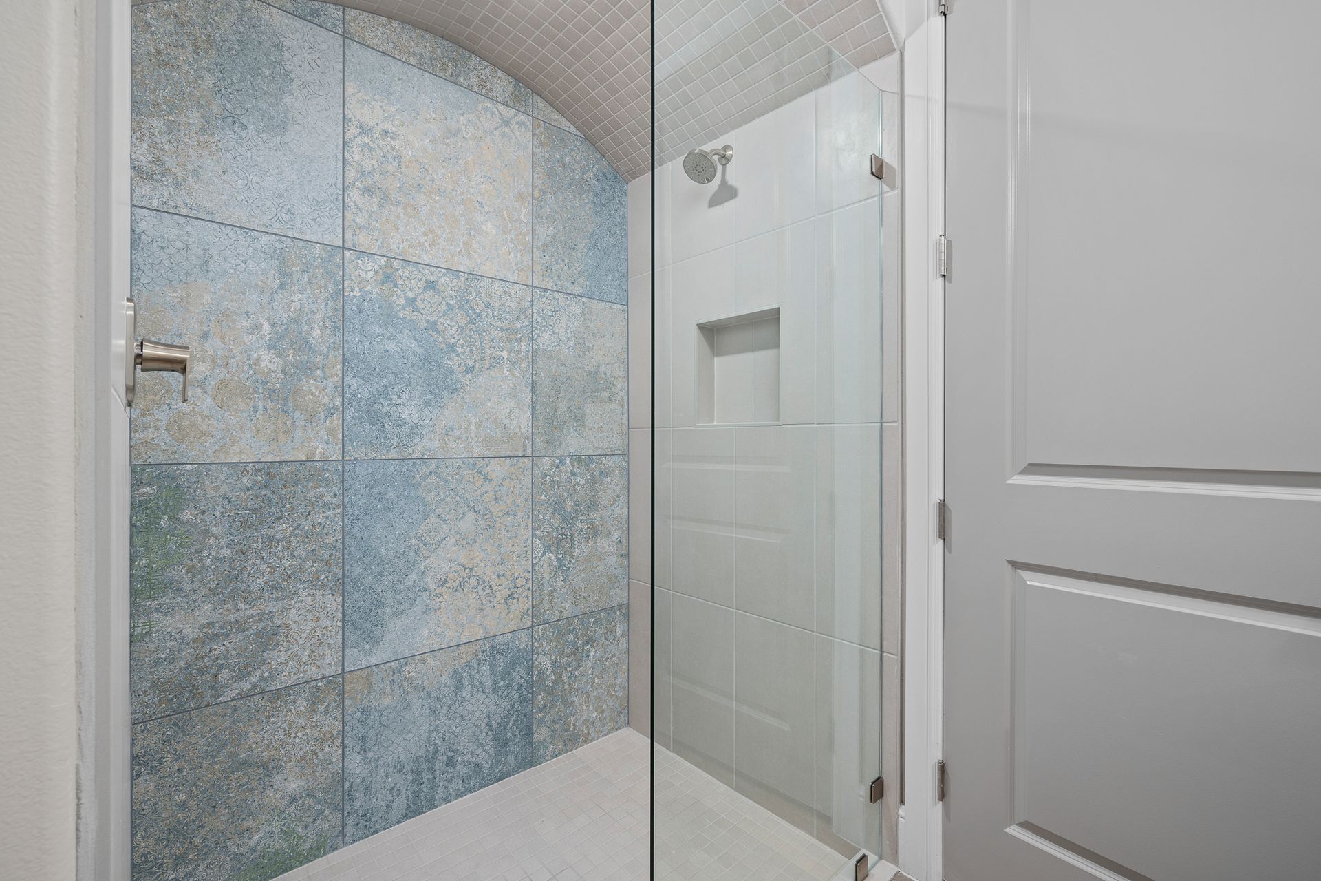 A bathroom with a walk in shower with a glass door.