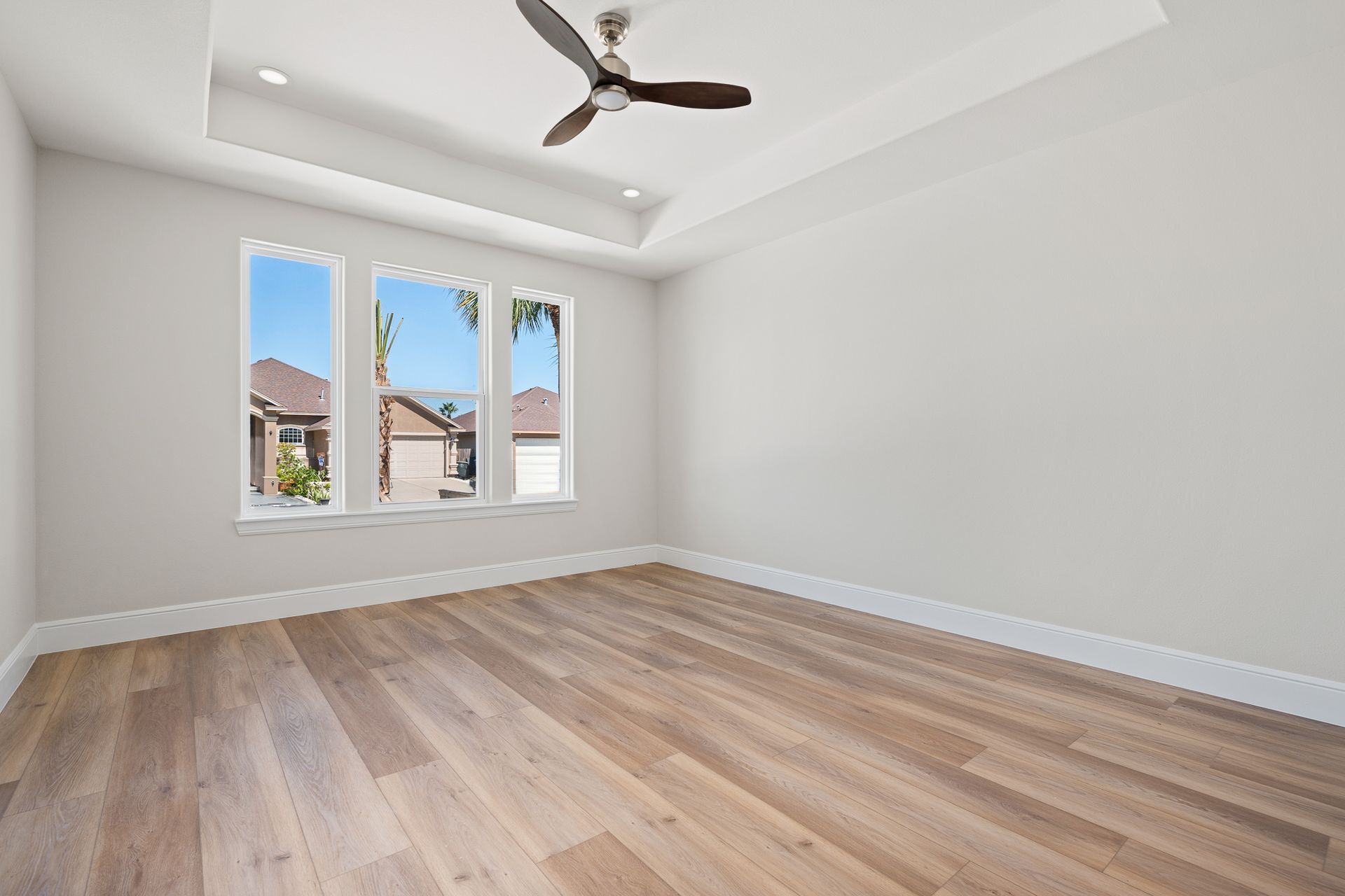 An empty room with hardwood floors and a ceiling fan.