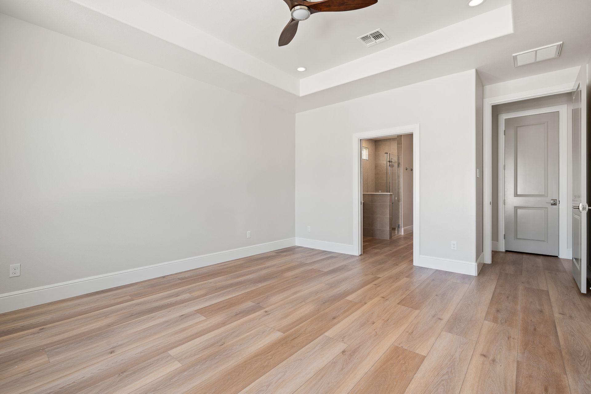 An empty bedroom with hardwood floors and a ceiling fan.