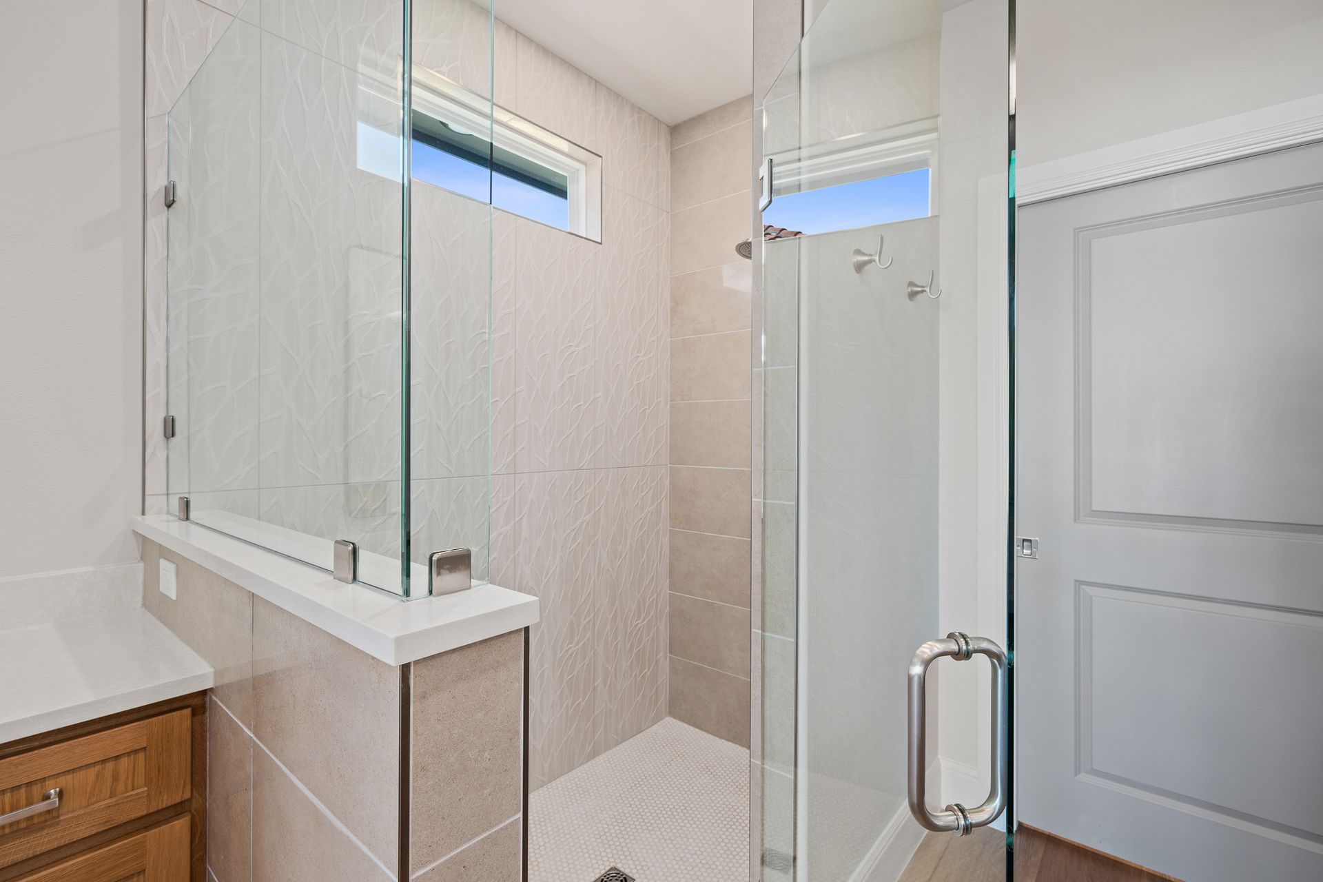 A bathroom with a walk in shower and a window.