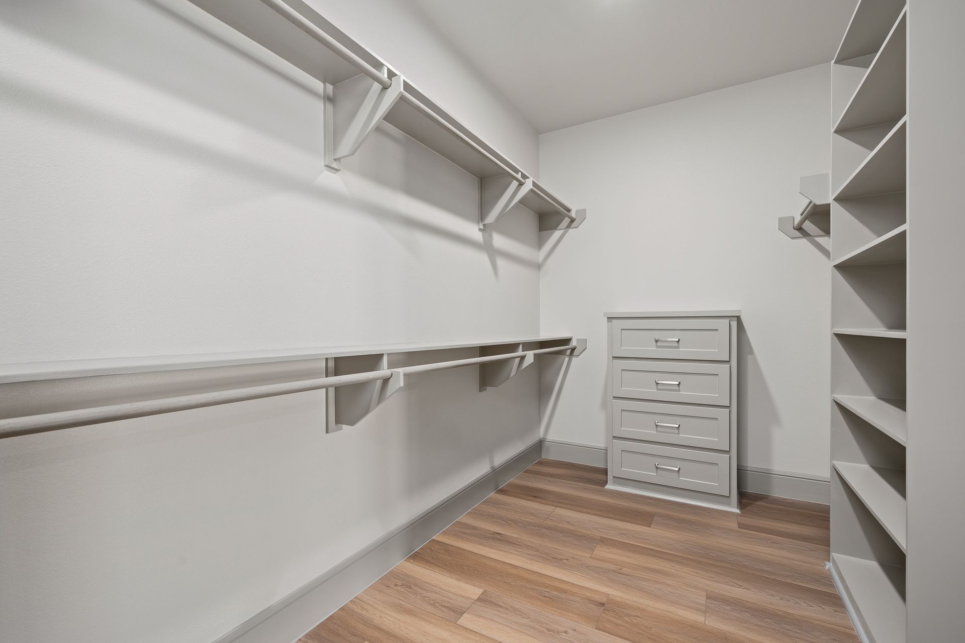 A walk in closet with lots of shelves and a dresser.