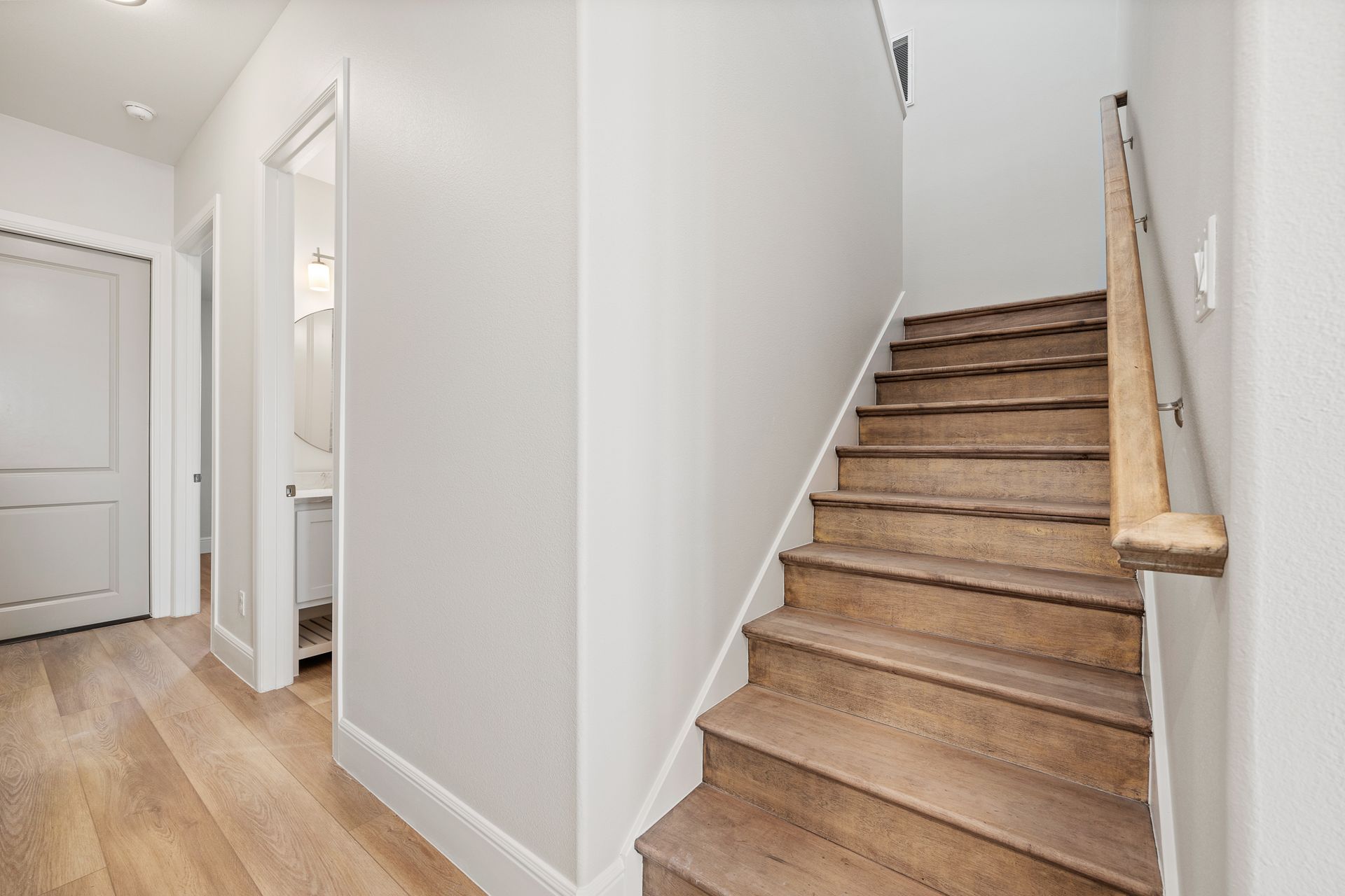 A hallway with wooden stairs leading up to the second floor of a house.