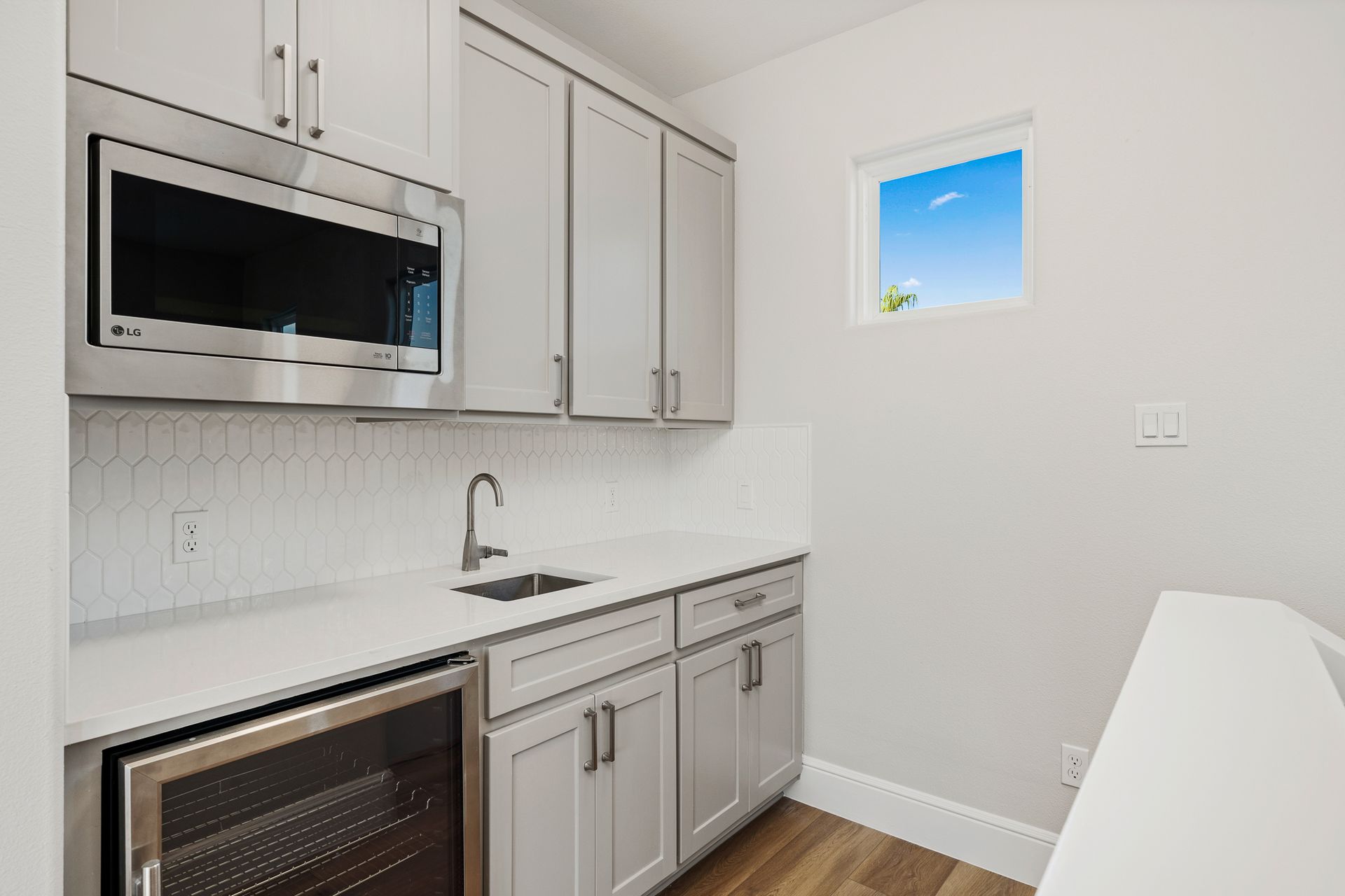 A kitchen with white cabinets , stainless steel appliances , a sink , and a window.