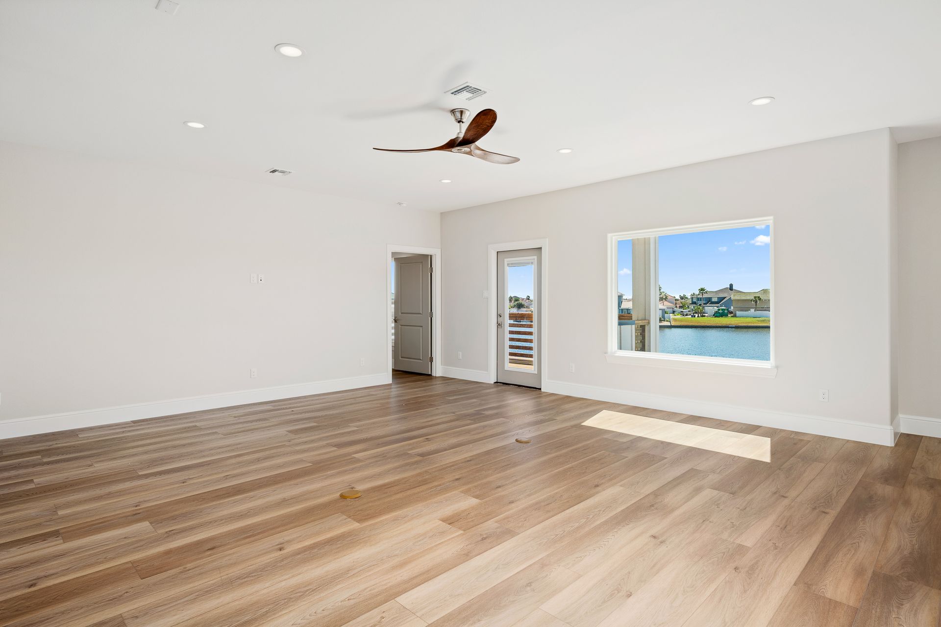 An empty living room with hardwood floors and a ceiling fan.