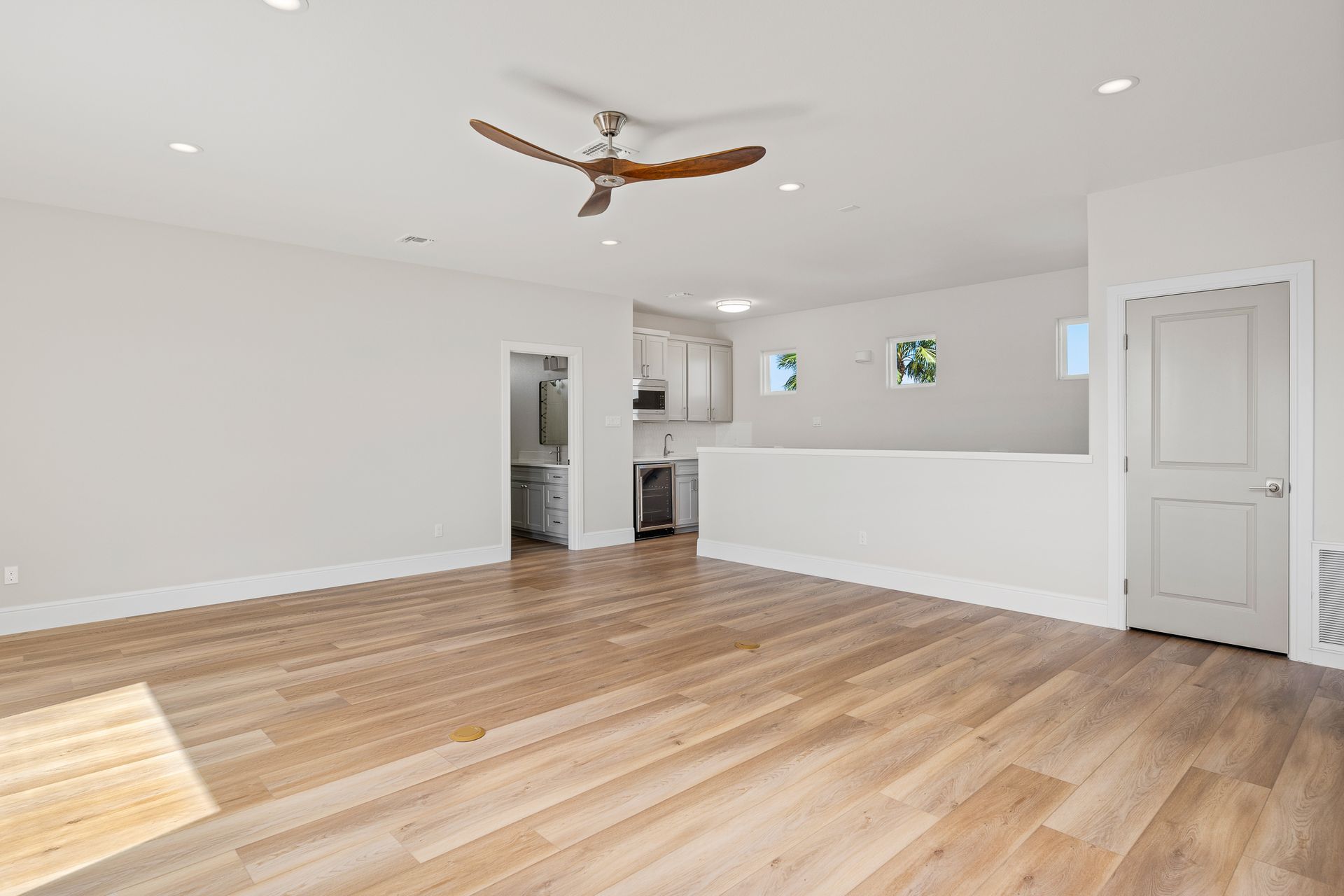 An empty living room with hardwood floors and a ceiling fan.