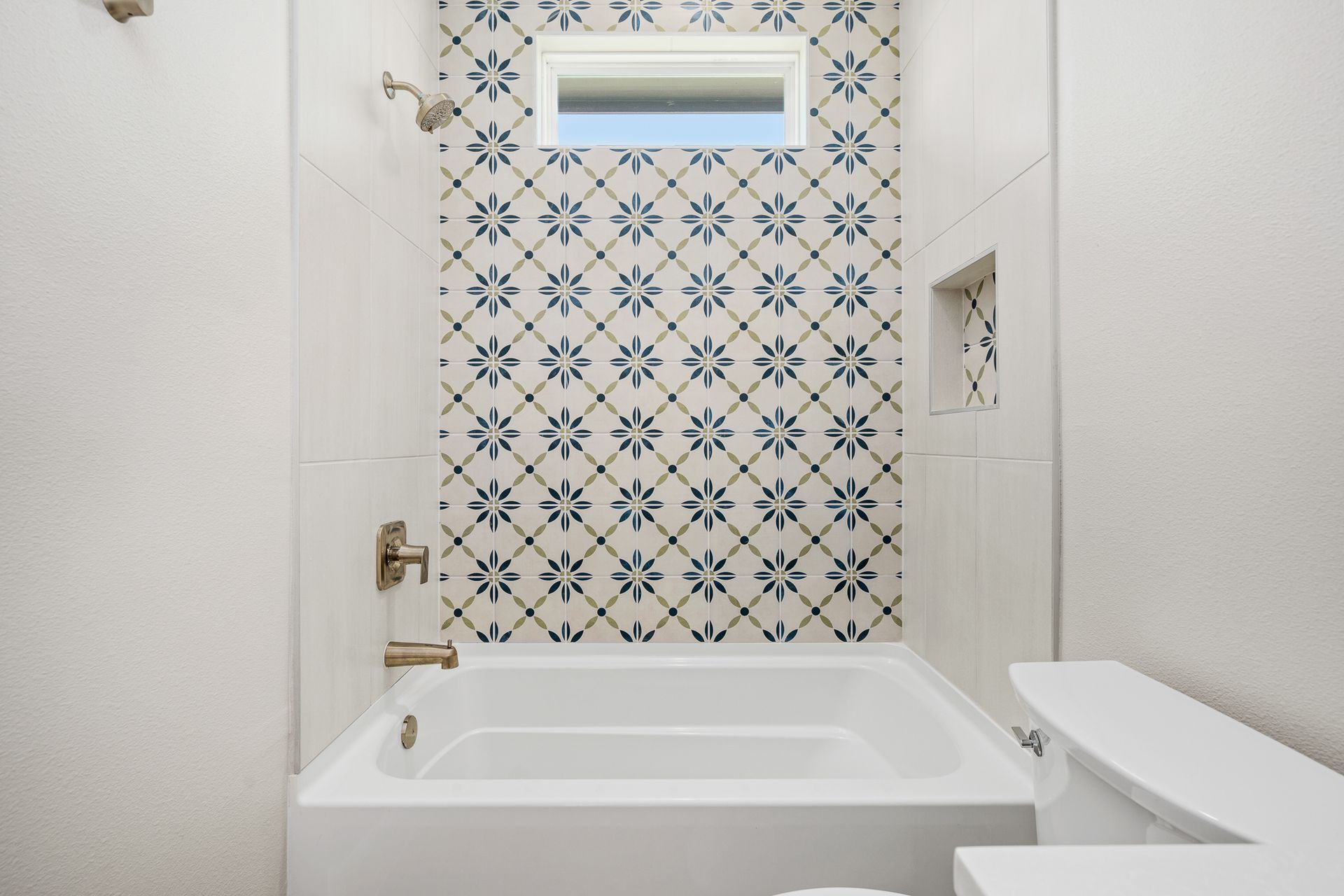A bathroom with a bathtub and a shower with a blue and white tile wall.
