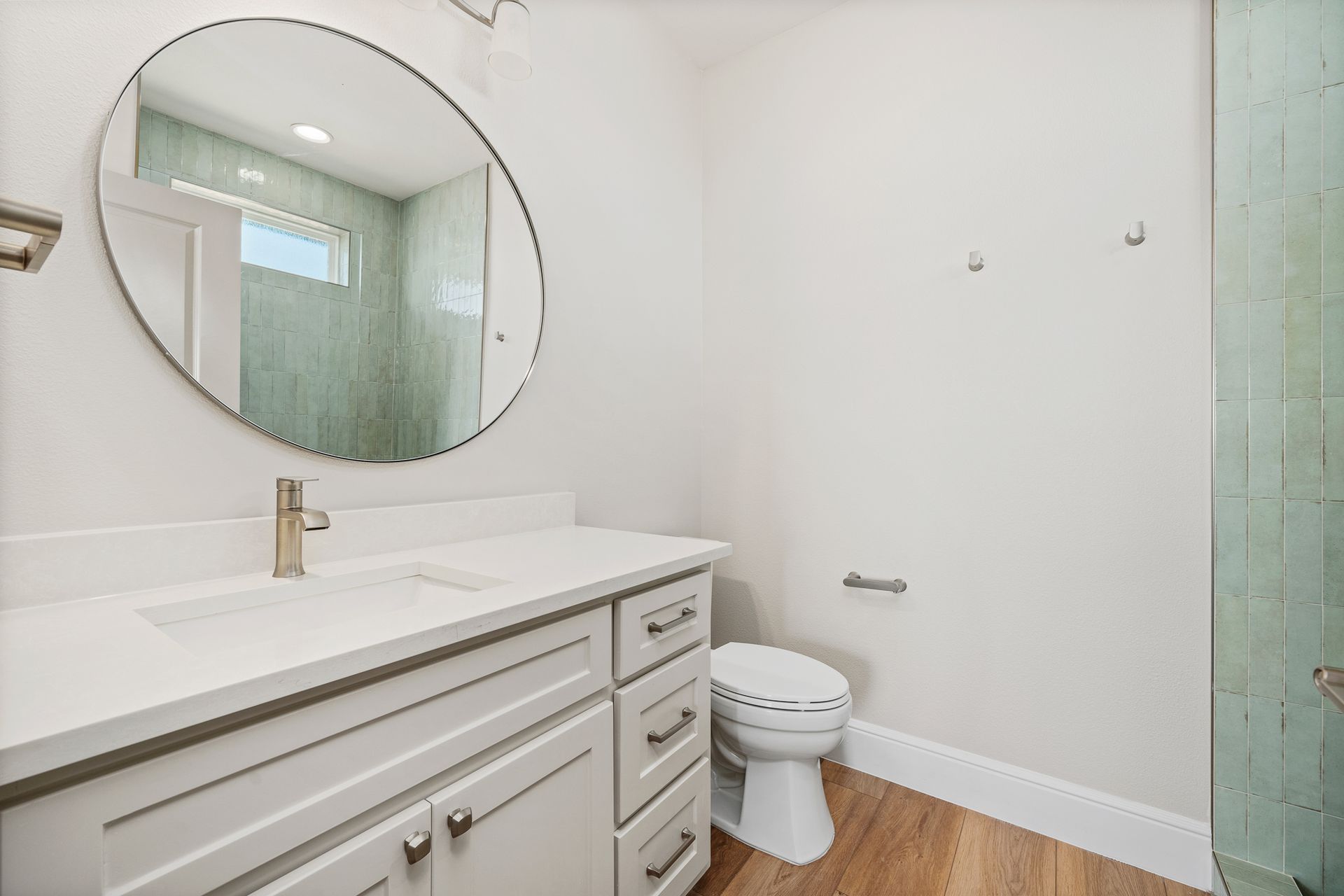 A bathroom with a toilet , sink and mirror.