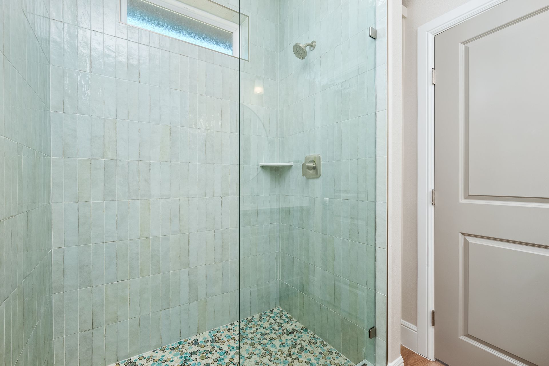 A bathroom with a walk in shower with a glass door.