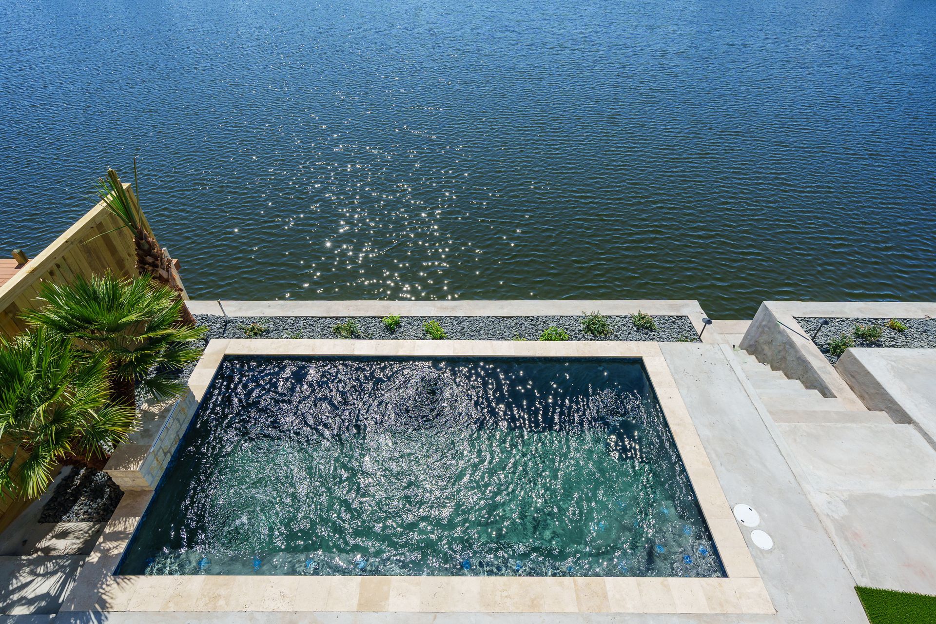 An aerial view of a swimming pool next to a body of water.