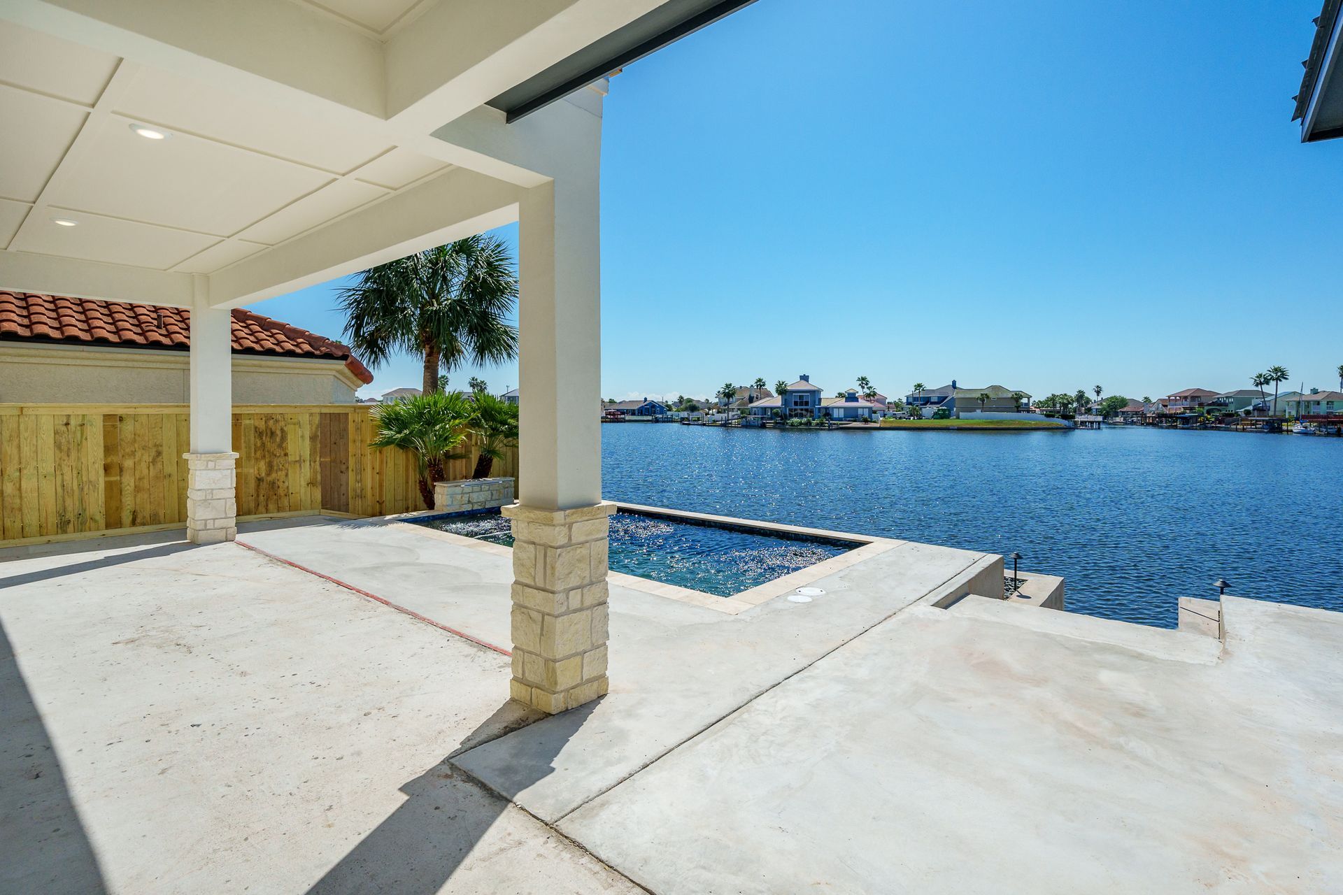 A patio with a view of a body of water and a swimming pool.