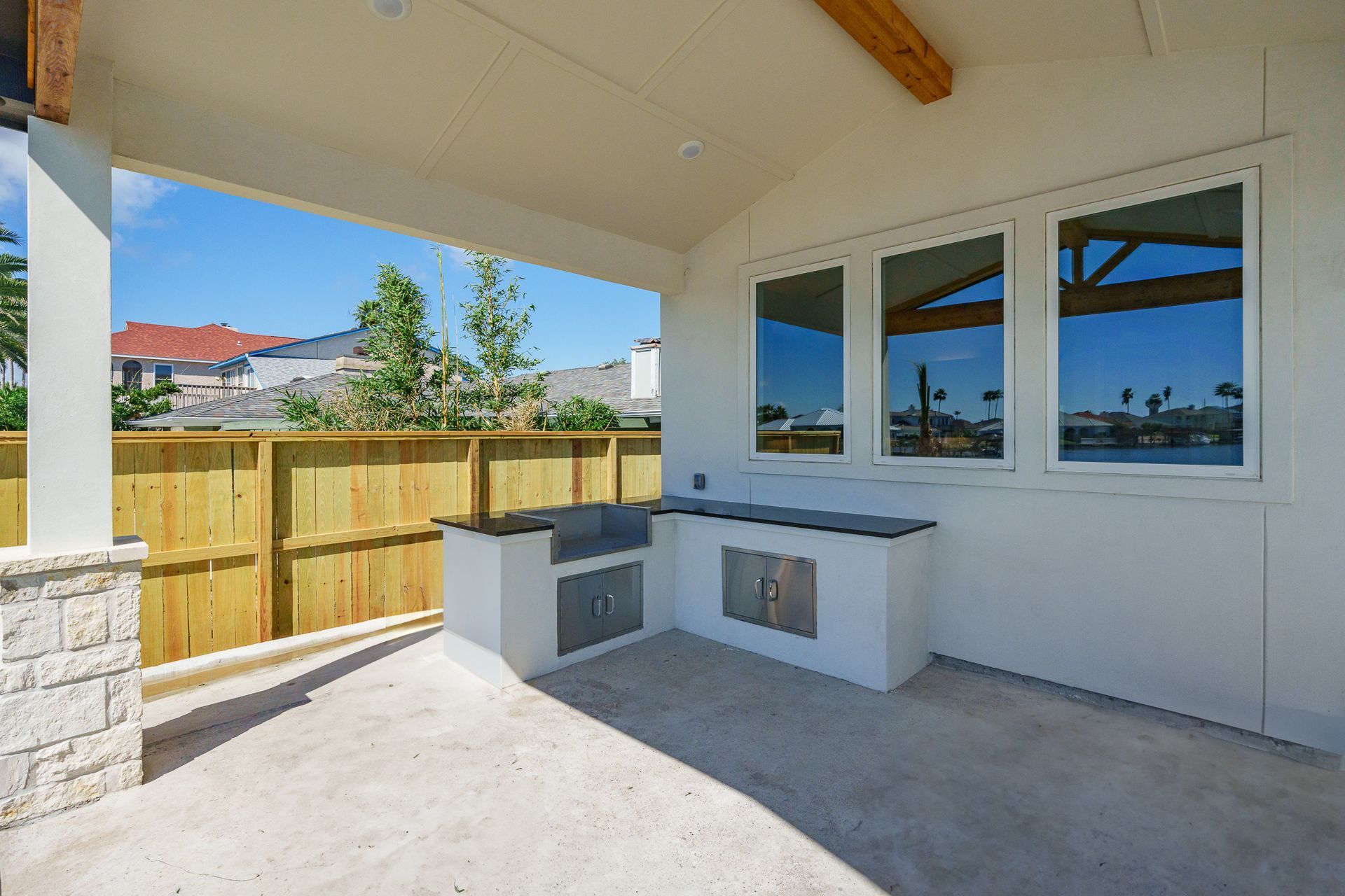 A patio with a grill and a fence in the background.