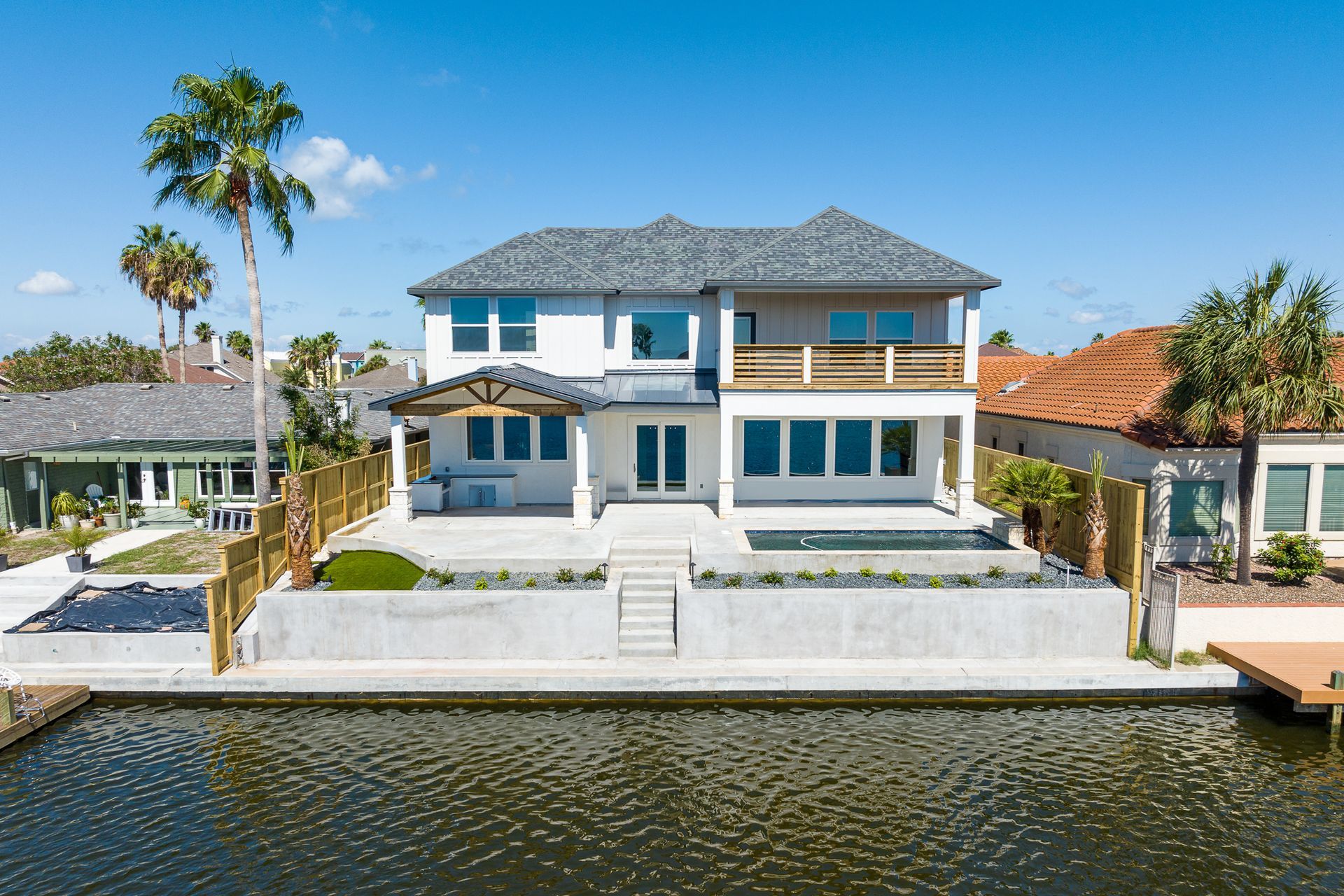 A large white house is sitting on top of a body of water.