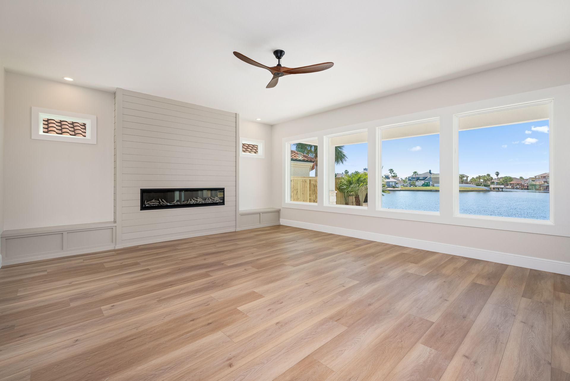 An empty living room with hardwood floors , a fireplace and a ceiling fan.