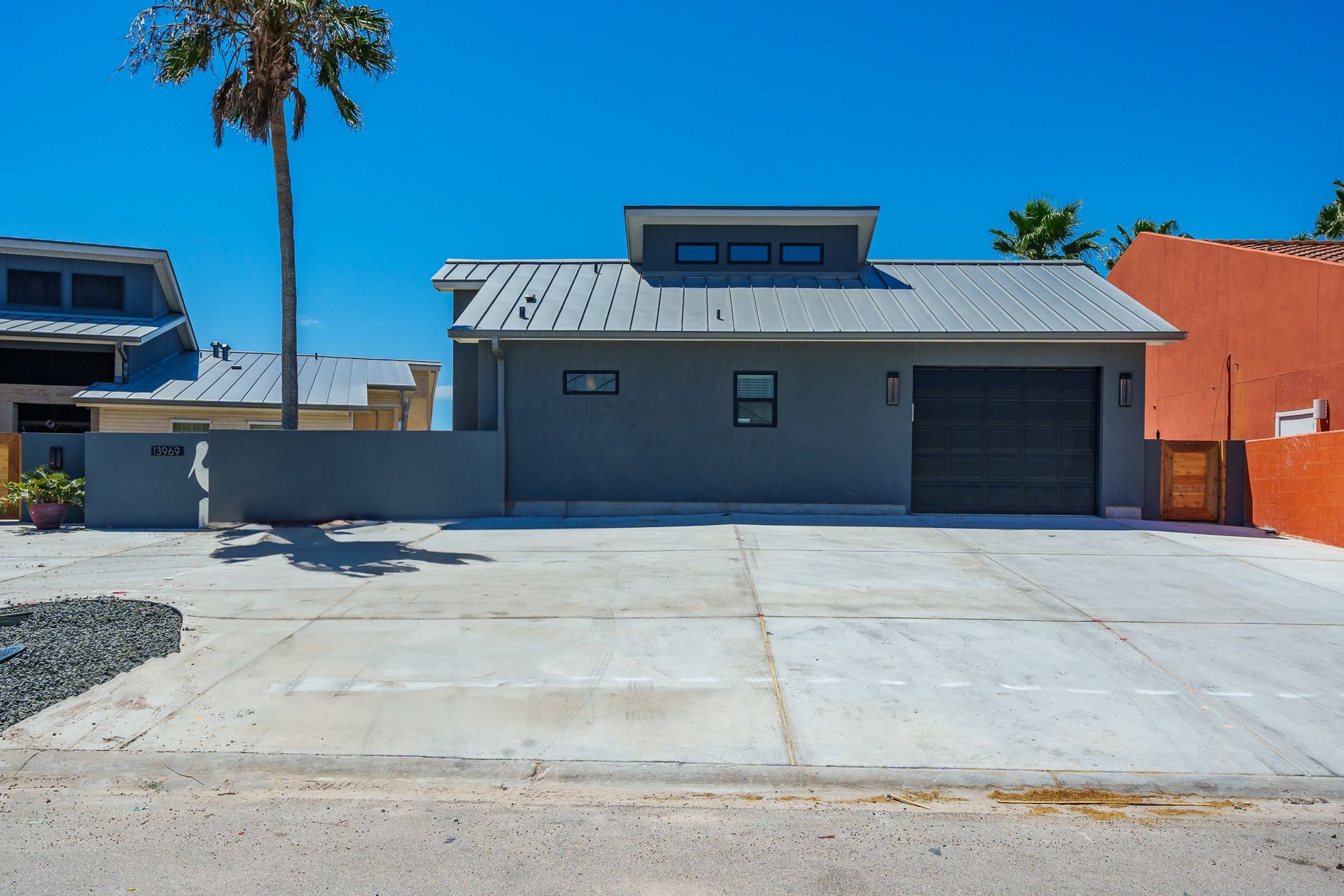 A house with a garage and a palm tree in front of it