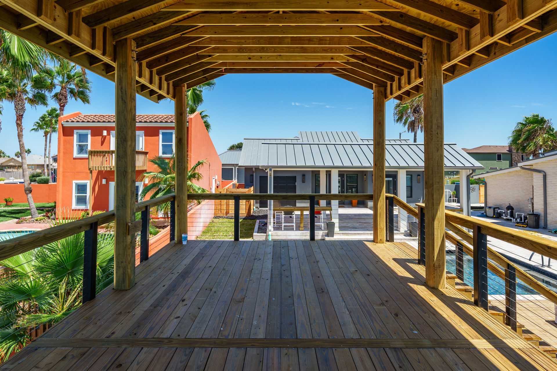 A wooden deck with a view of a house and a pool.