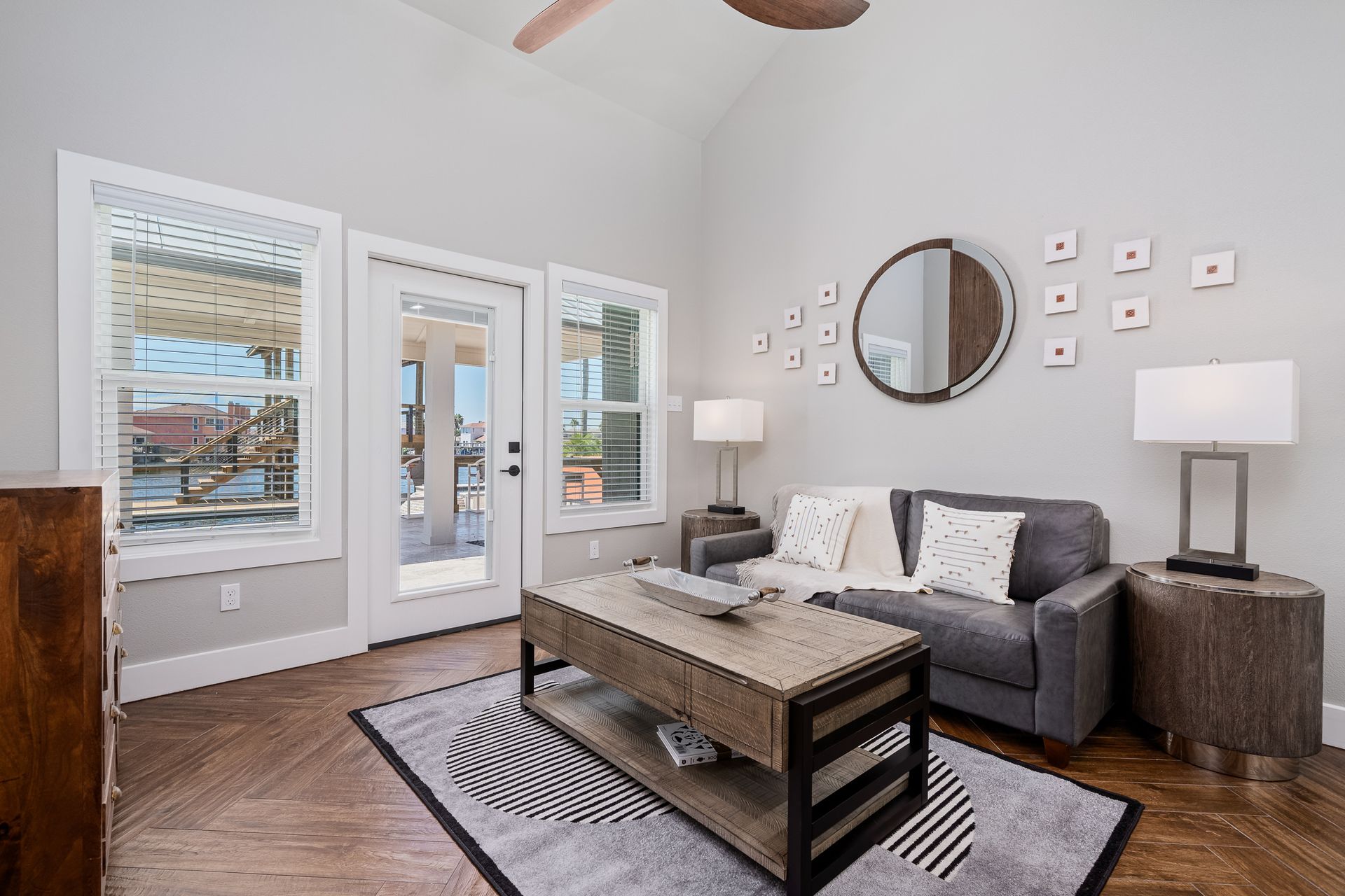 A living room with a couch , coffee table , lamp and mirror.