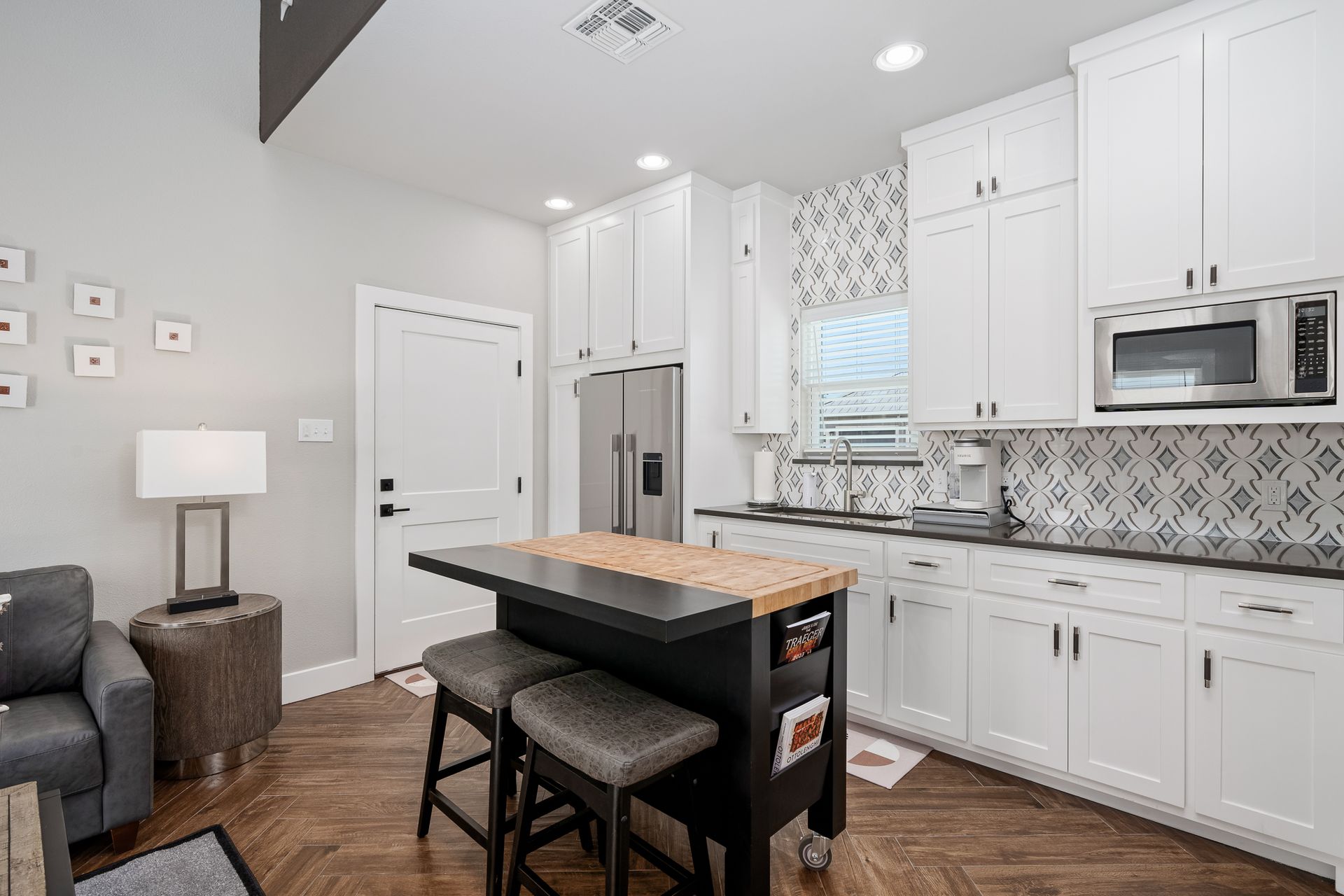 A kitchen with white cabinets , granite counter tops , stainless steel appliances and a large island.
