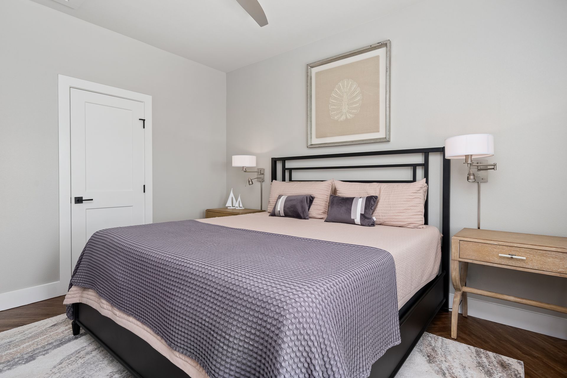 A bedroom with a bed , nightstand , lamp and a ceiling fan.