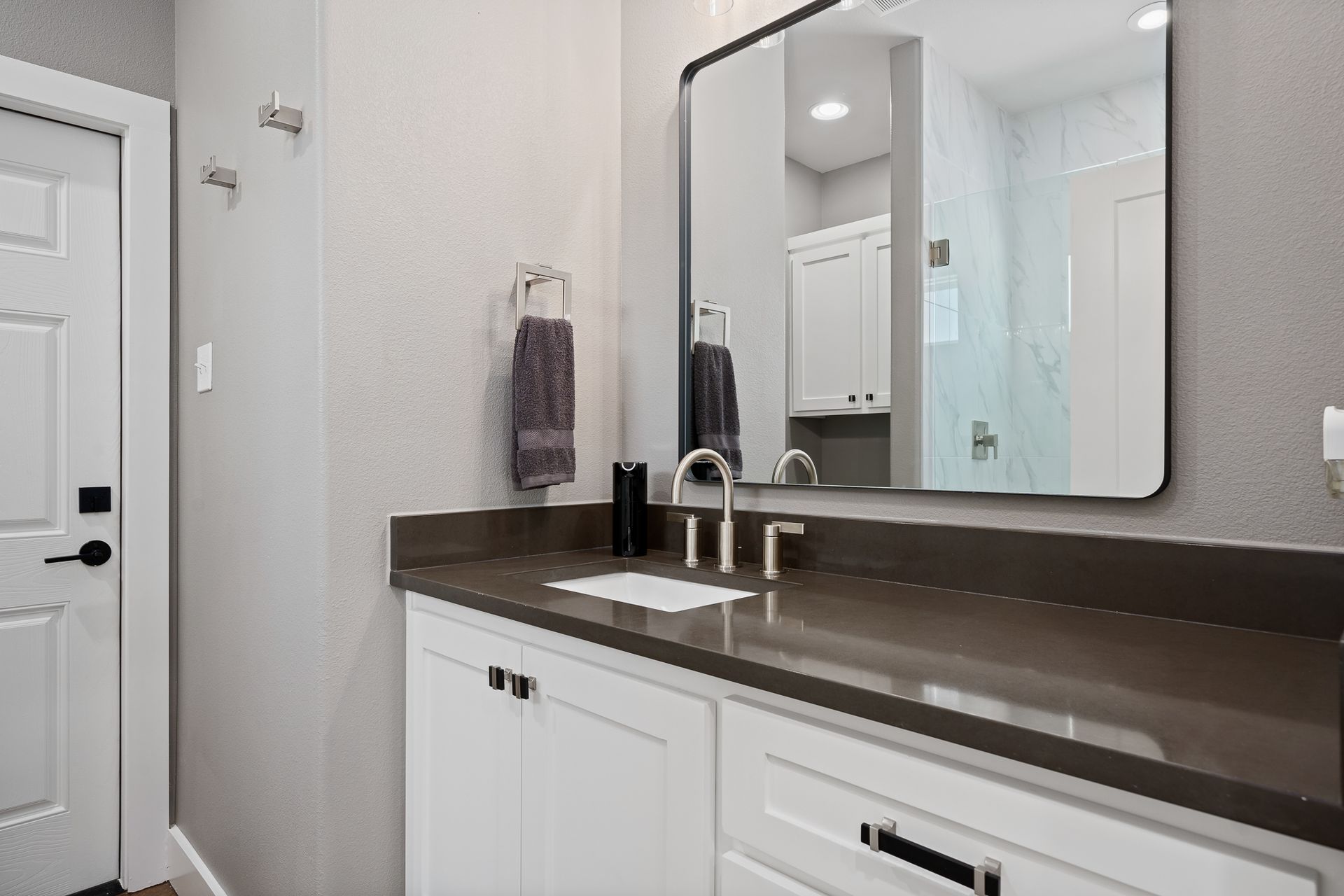 A bathroom with a sink , mirror and cabinets.