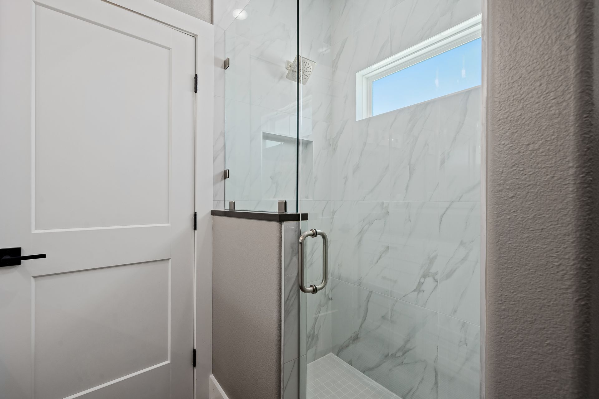 A bathroom with a walk in shower with a glass door.
