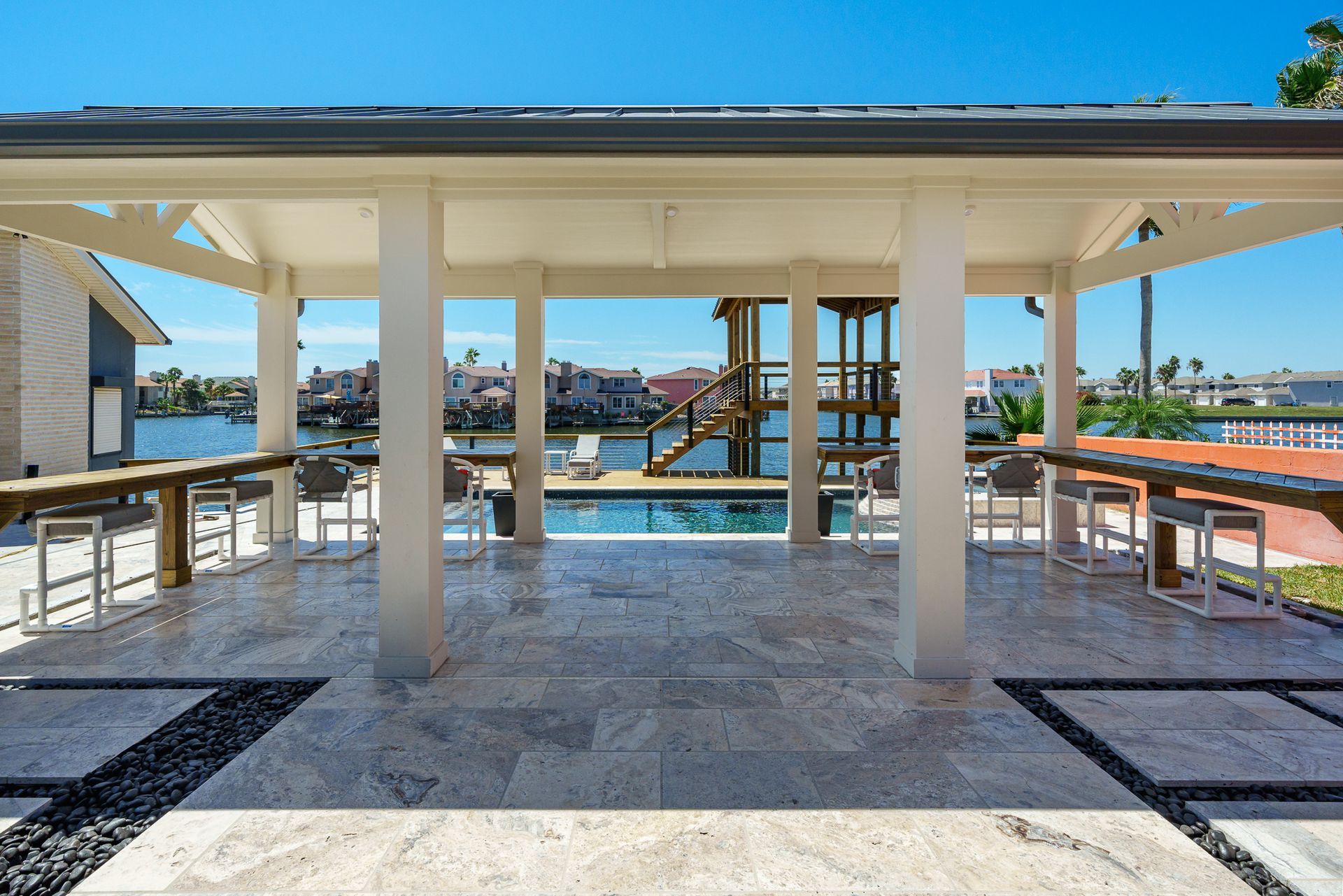 A gazebo overlooking a pool with tables and chairs
