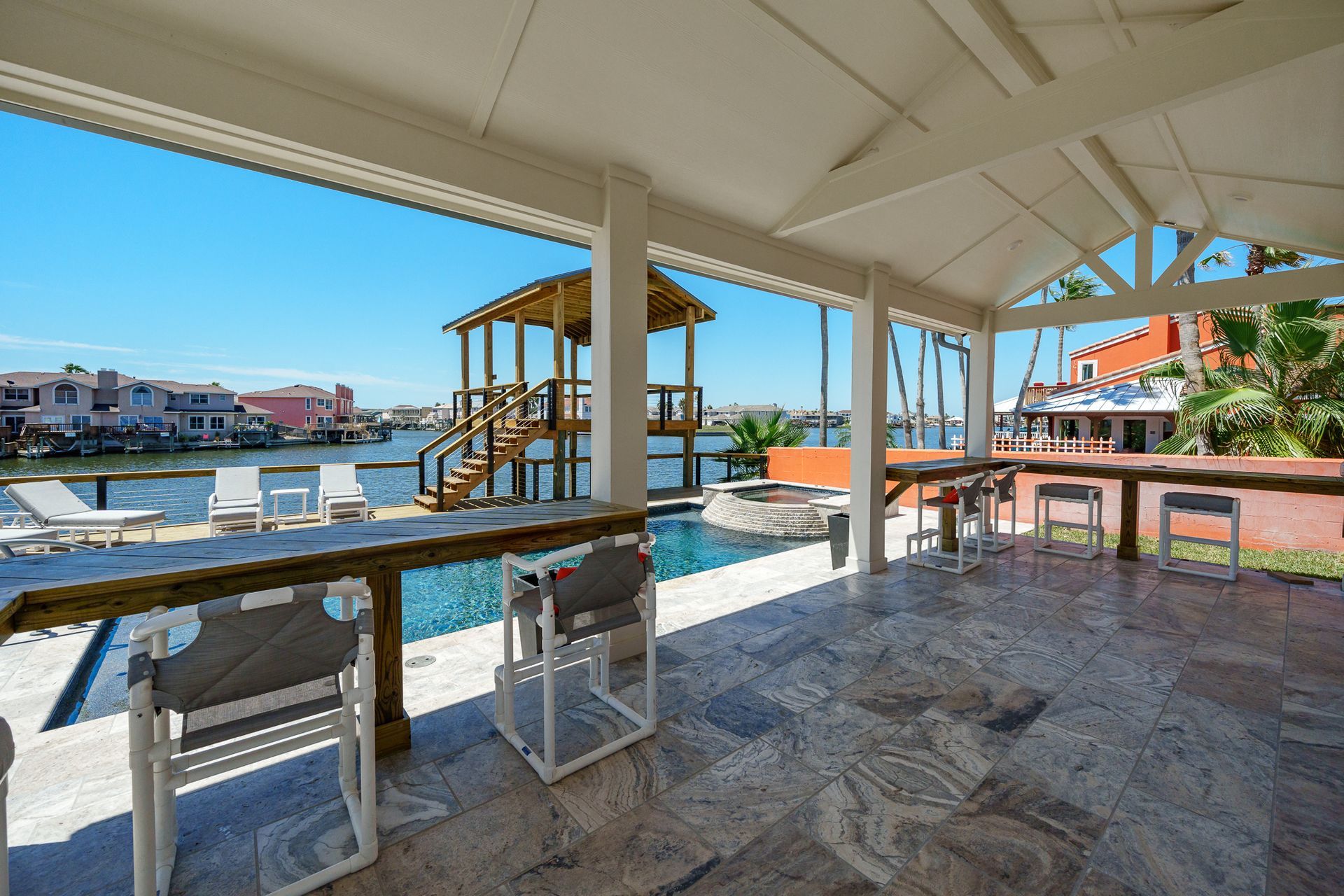 A covered area with tables and chairs overlooking a swimming pool