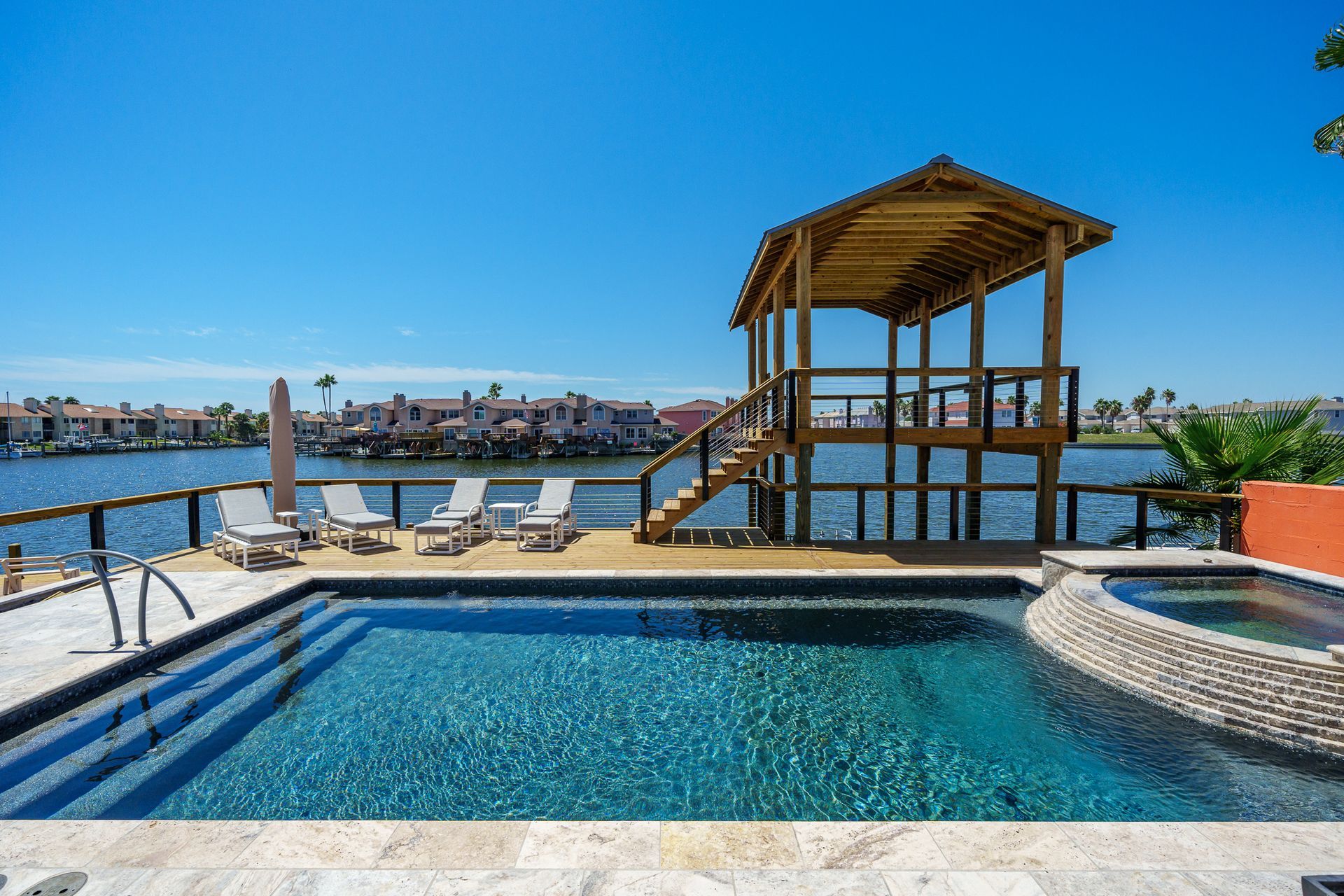 A large swimming pool surrounded by chairs and a gazebo overlooking a body of water.
