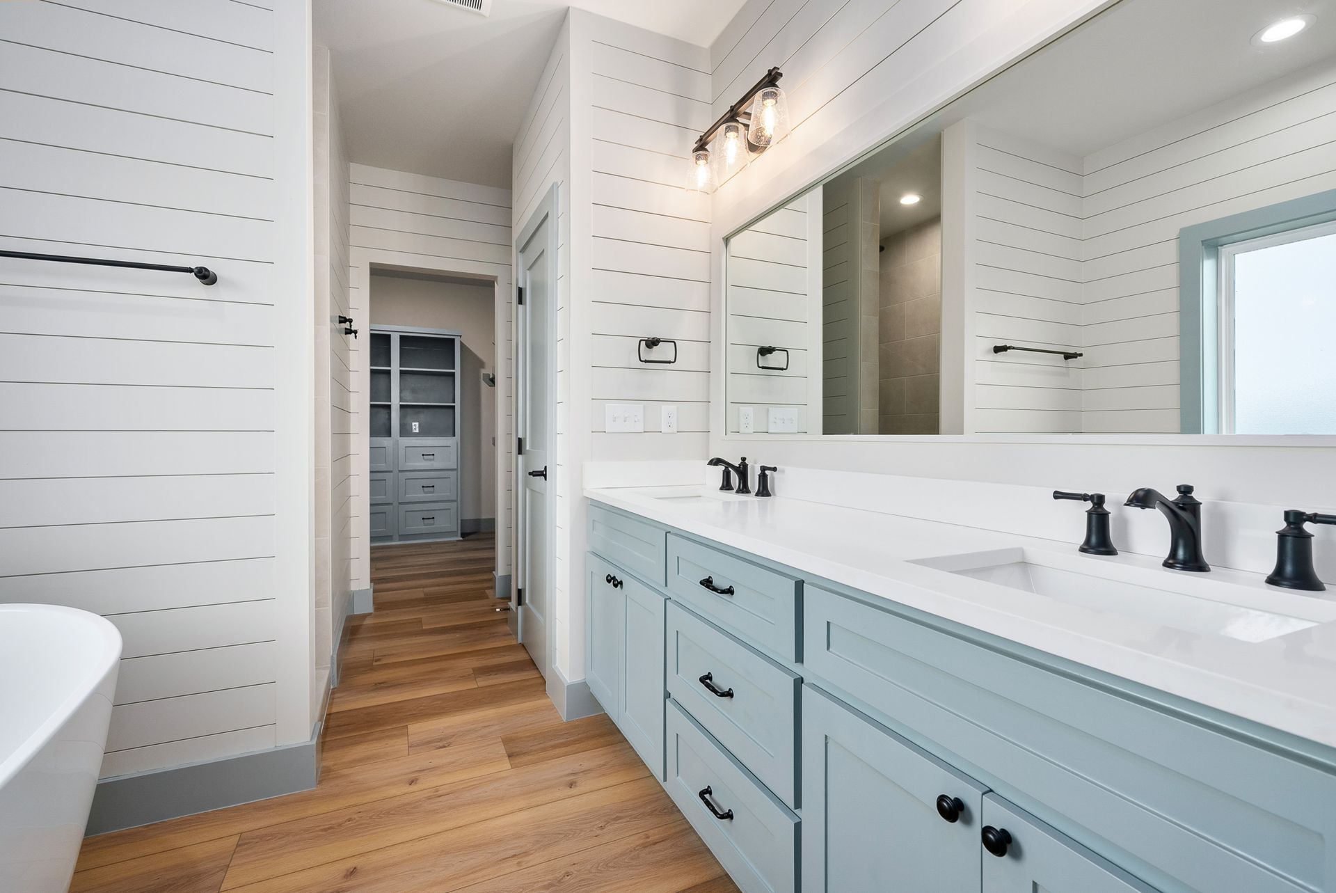 Bathroom with blue cabinets, white countertops, and wood flooring.