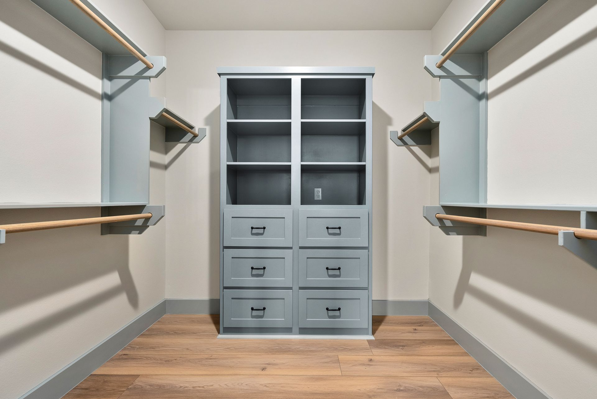 Walk-in closet with blue shelving, drawers, and hanging rods; light wood-look floor.