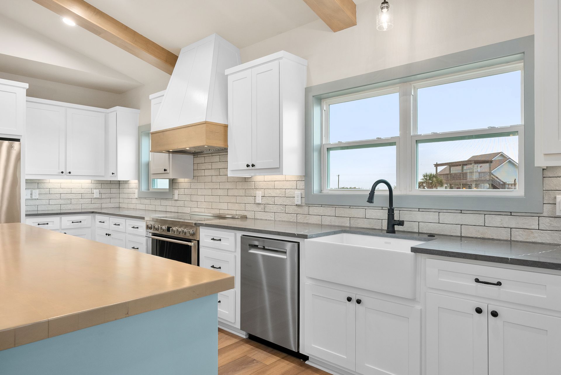 White kitchen with pale blue island and stainless steel appliances.