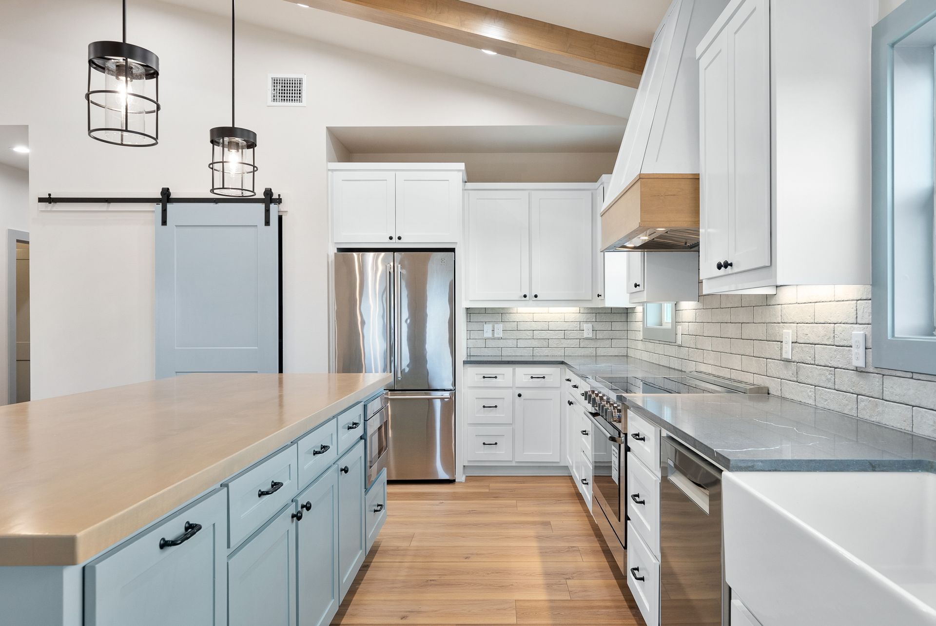 Modern kitchen with a blue island, white cabinets, and stainless steel appliances.
