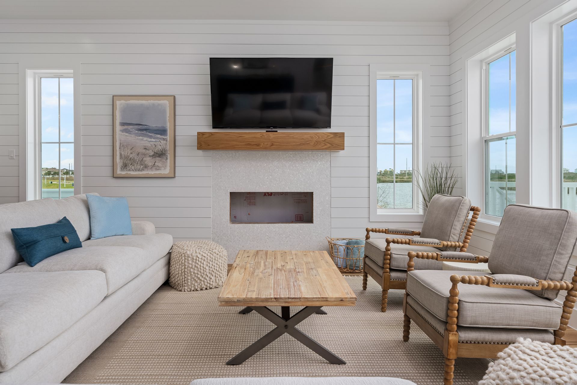 A living room with a couch , chairs , coffee table and television.