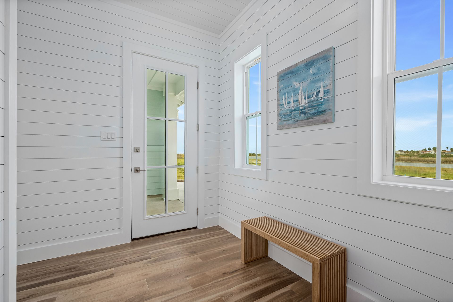 A hallway with a bench and a painting on the wall.