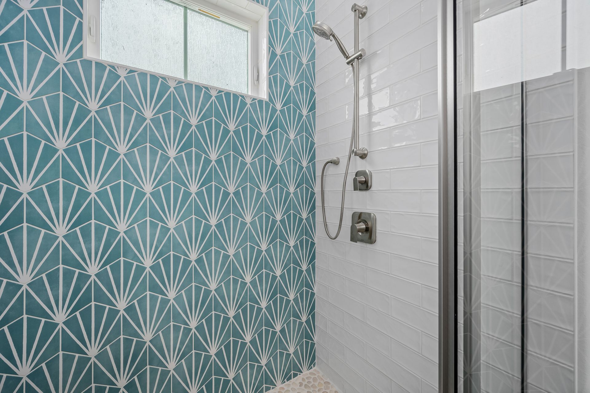 There is a shower with a blue wall and white tiles.