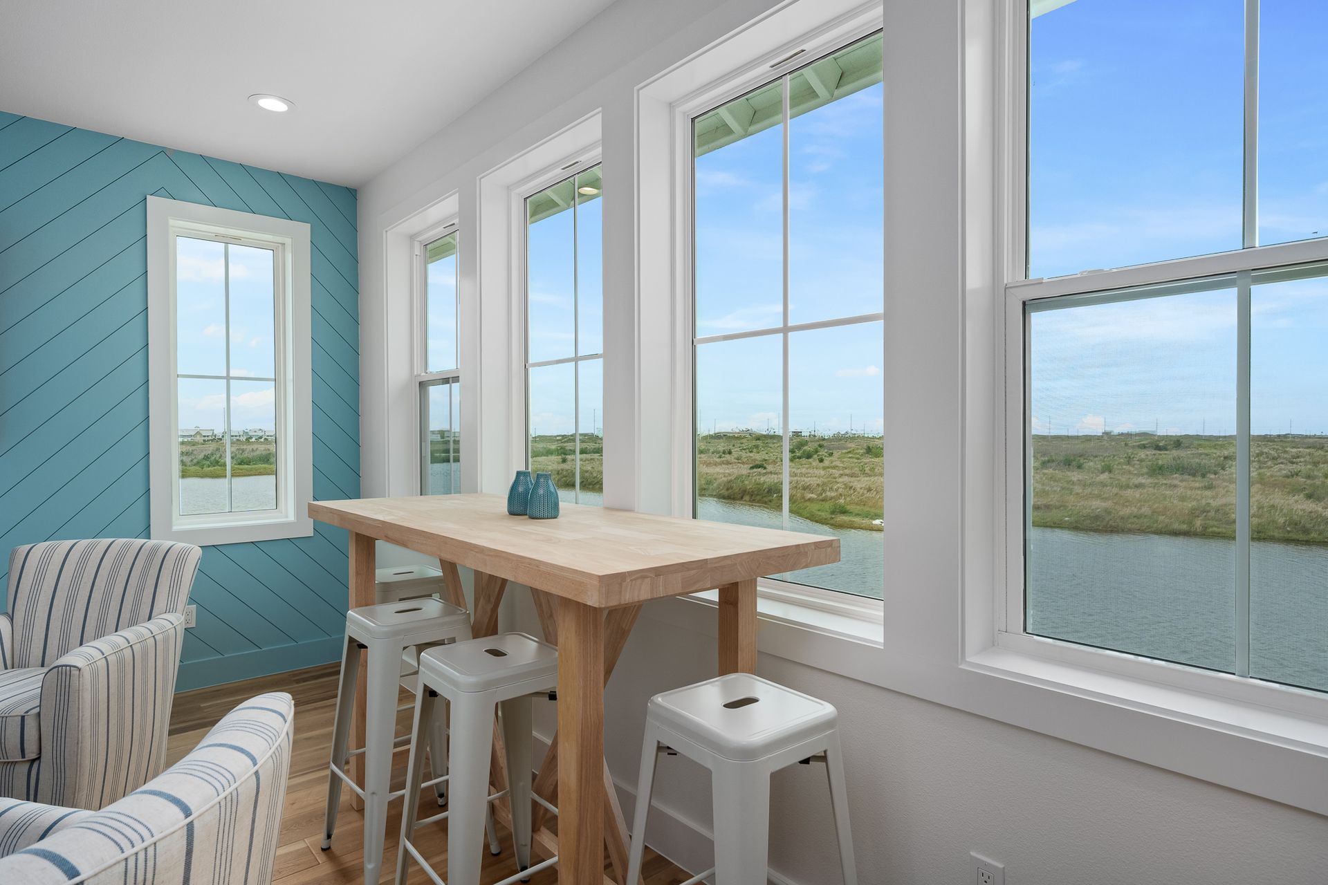 A living room with a table and stools and a view of a lake.