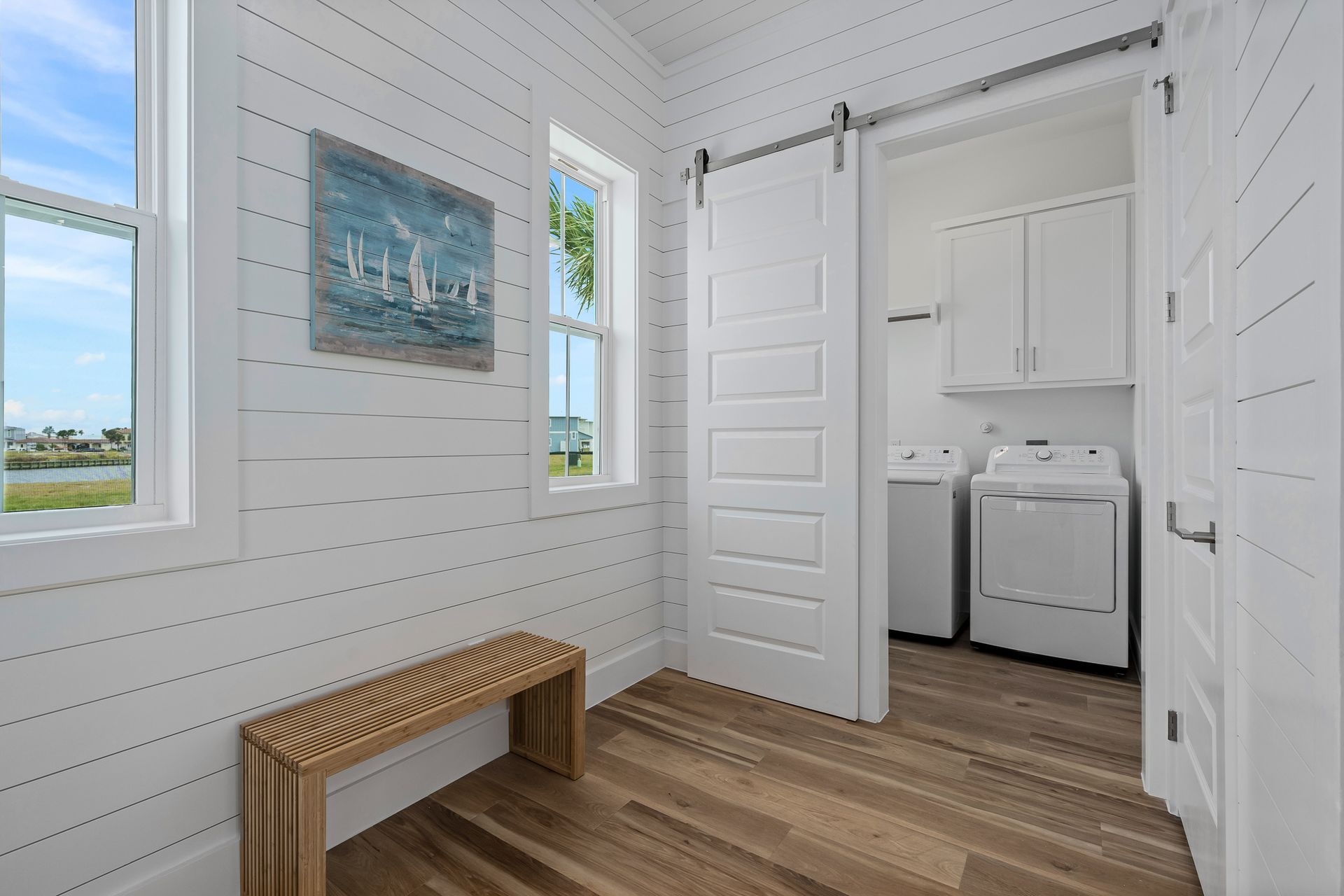 A laundry room with a sliding barn door and a bench.