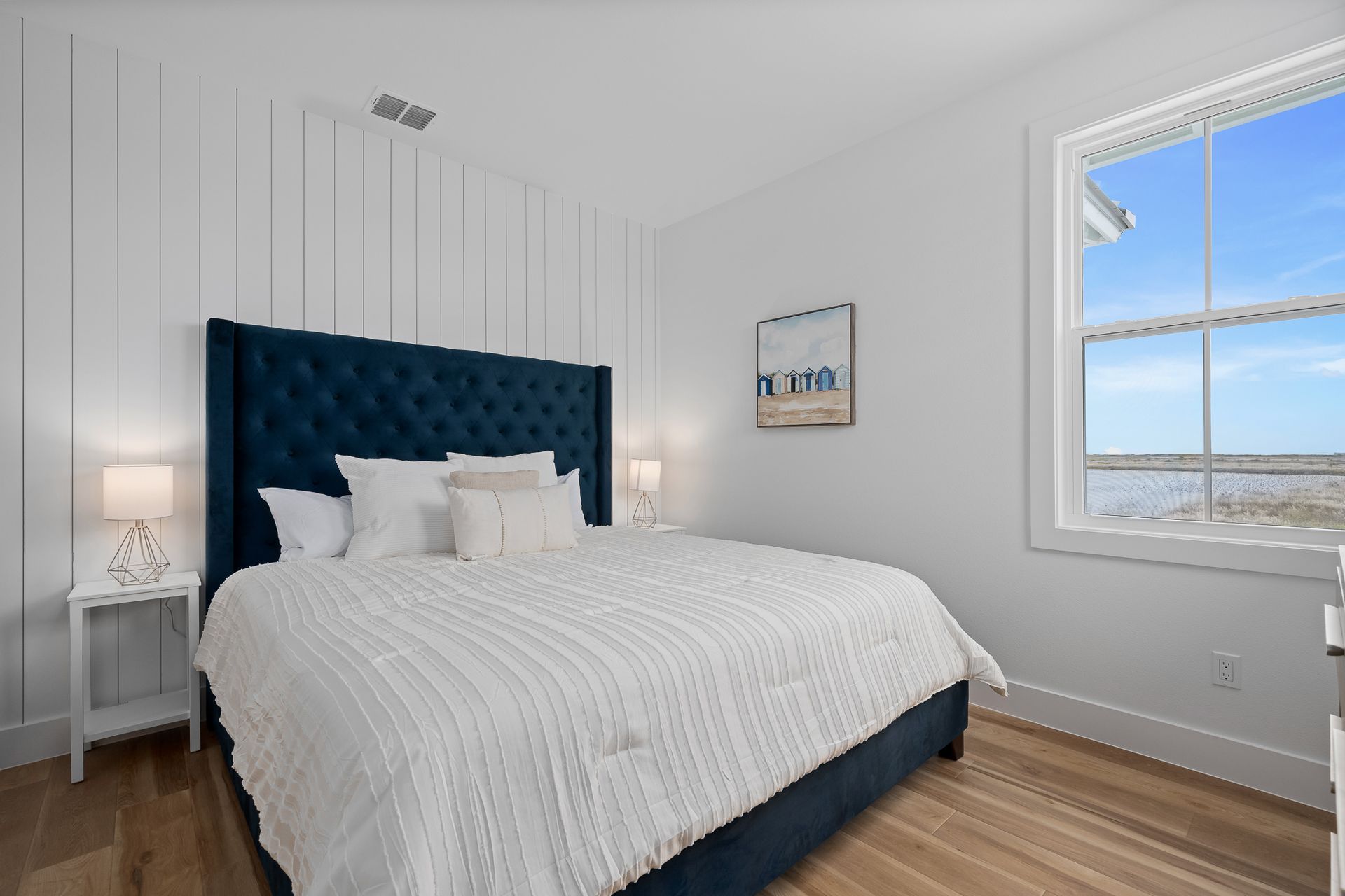 A bedroom with a large bed and a window with a view of the ocean.