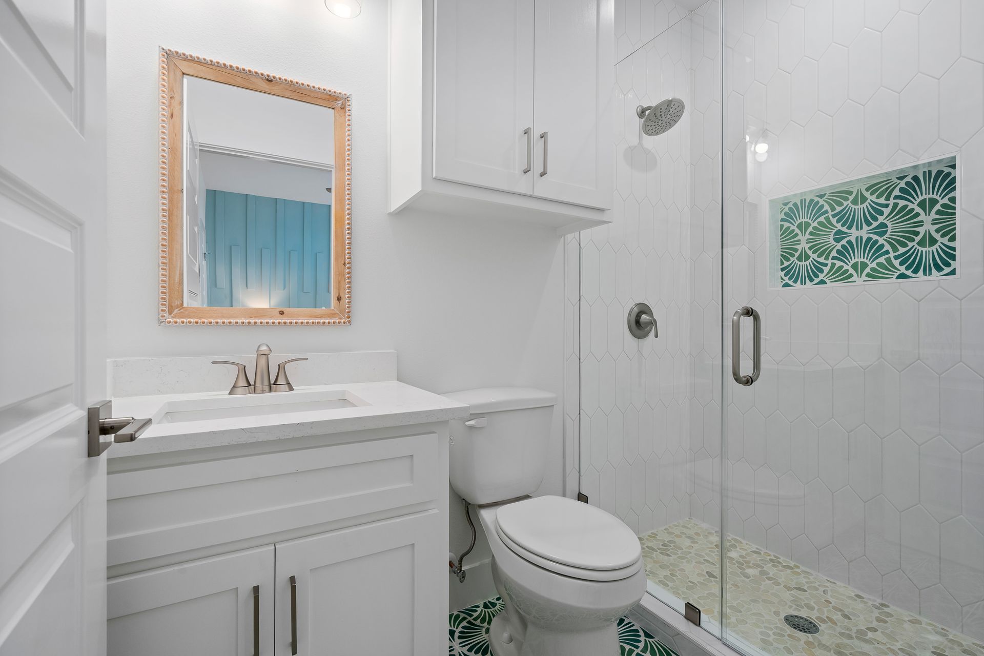 A bathroom with a toilet , sink , mirror and shower.