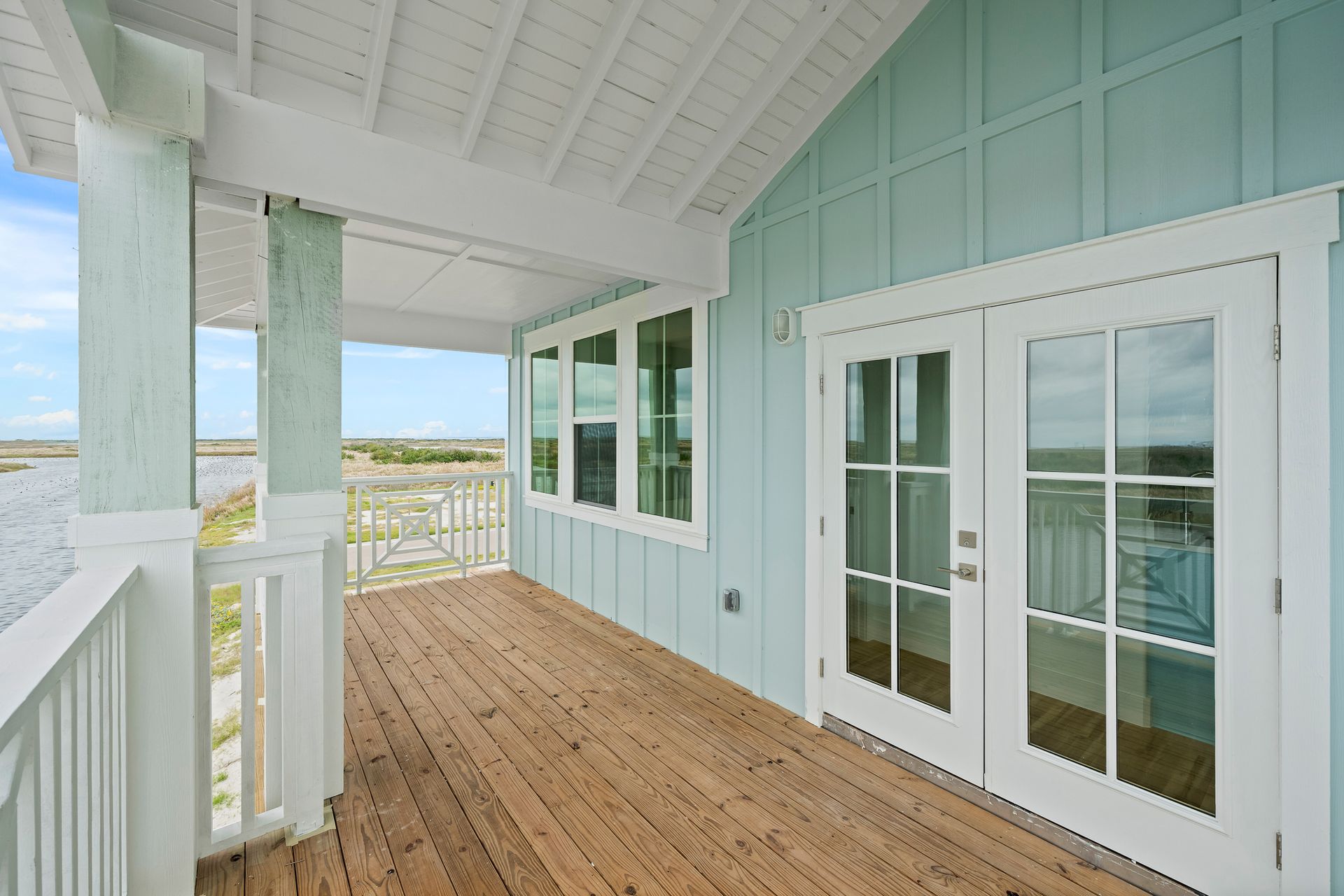 A blue house with a wooden deck and sliding glass doors