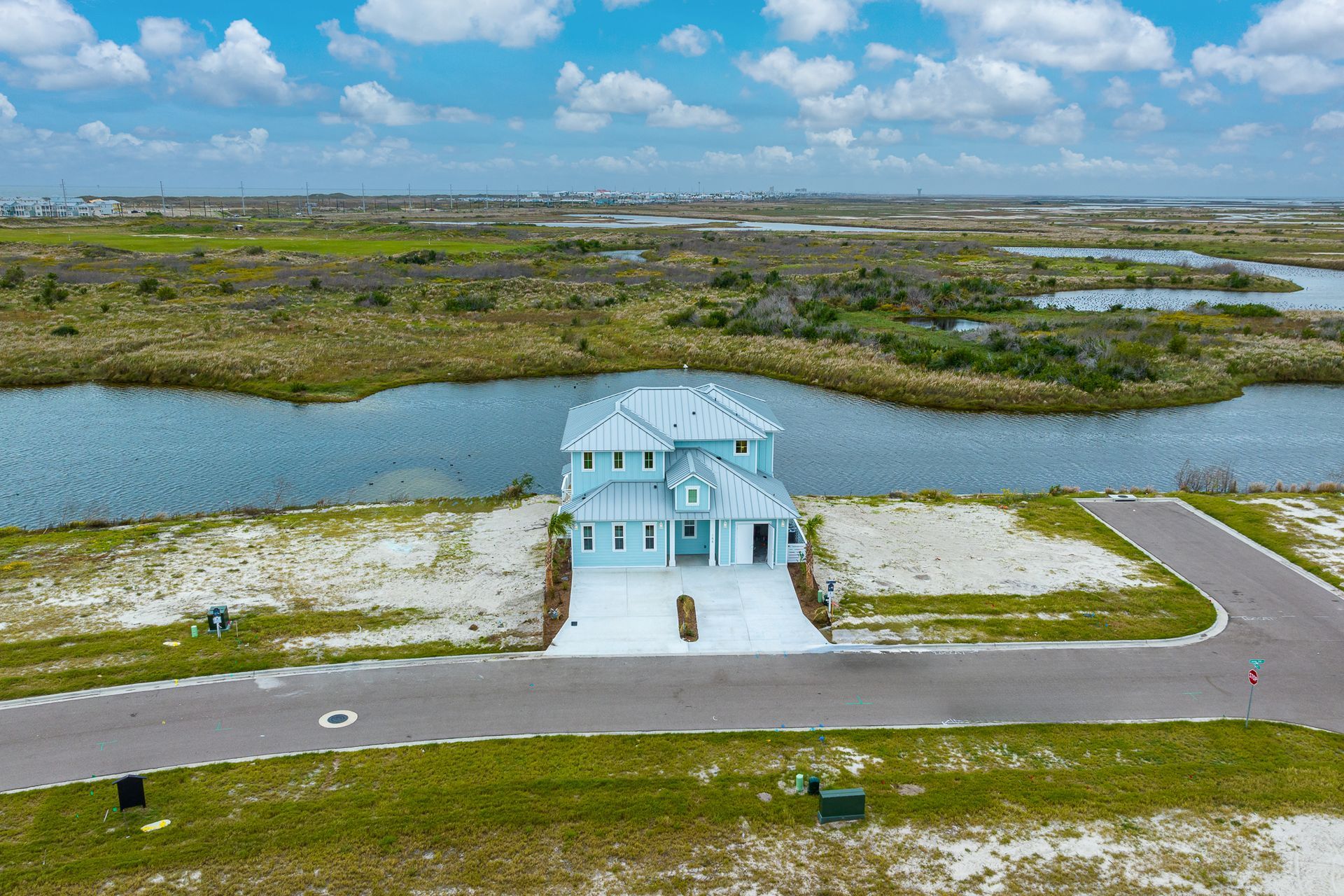 An aerial view of a house surrounded by water and grass.