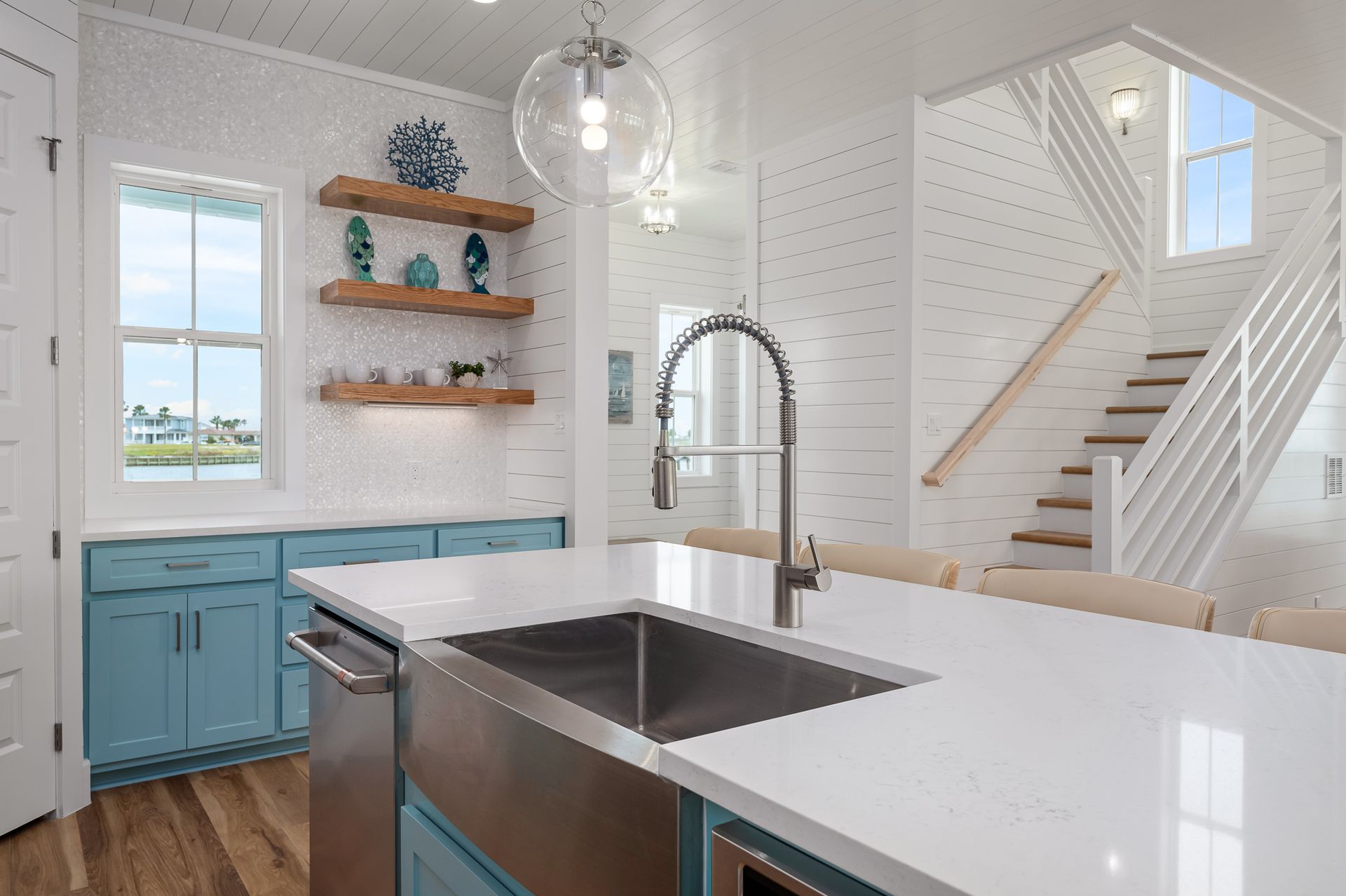 A kitchen with a sink and stairs in the background