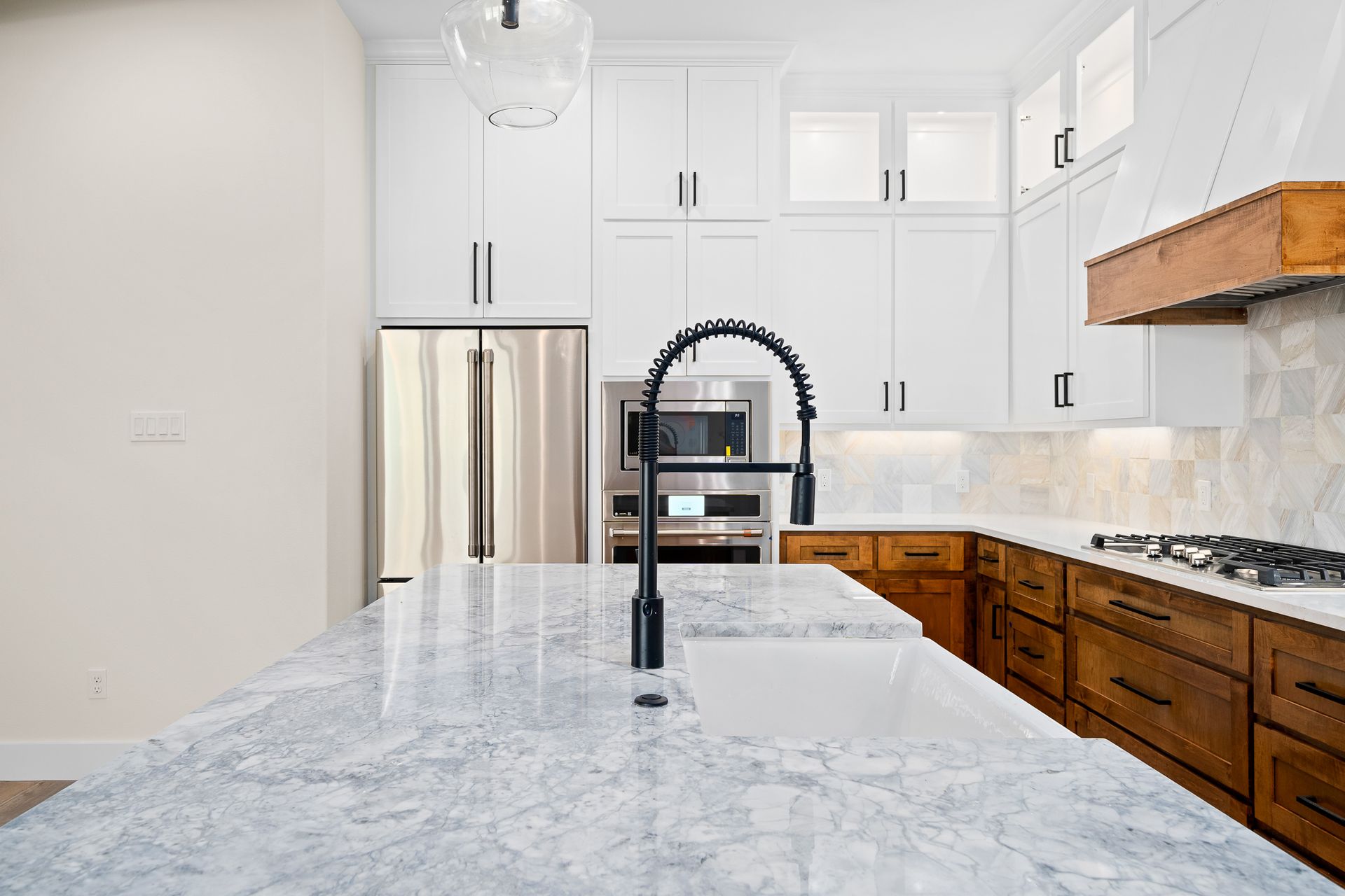 A kitchen with white cabinets , granite counter tops , stainless steel appliances and a sink.