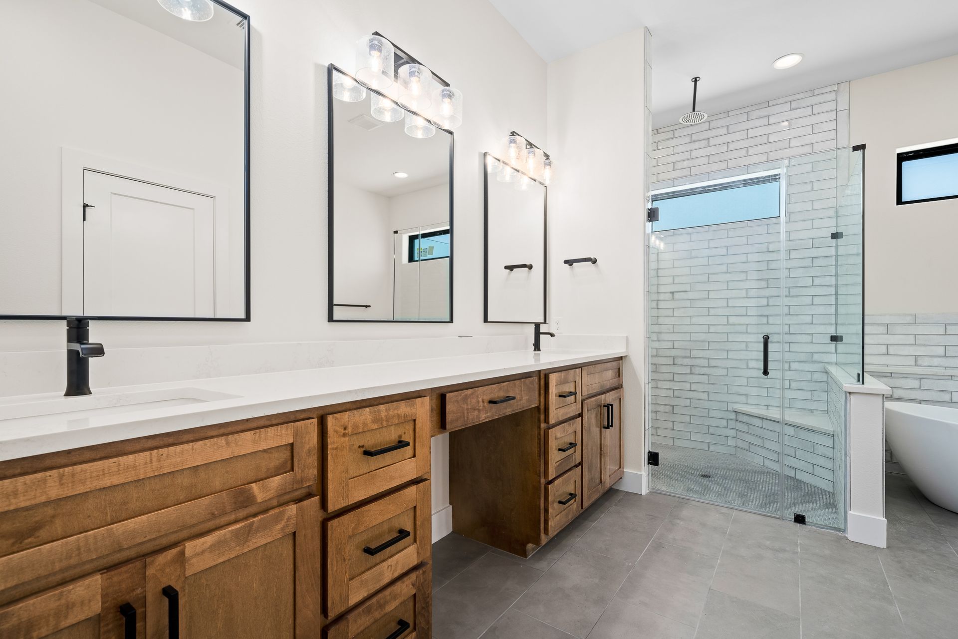 A bathroom with two sinks , two mirrors and a walk in shower.
