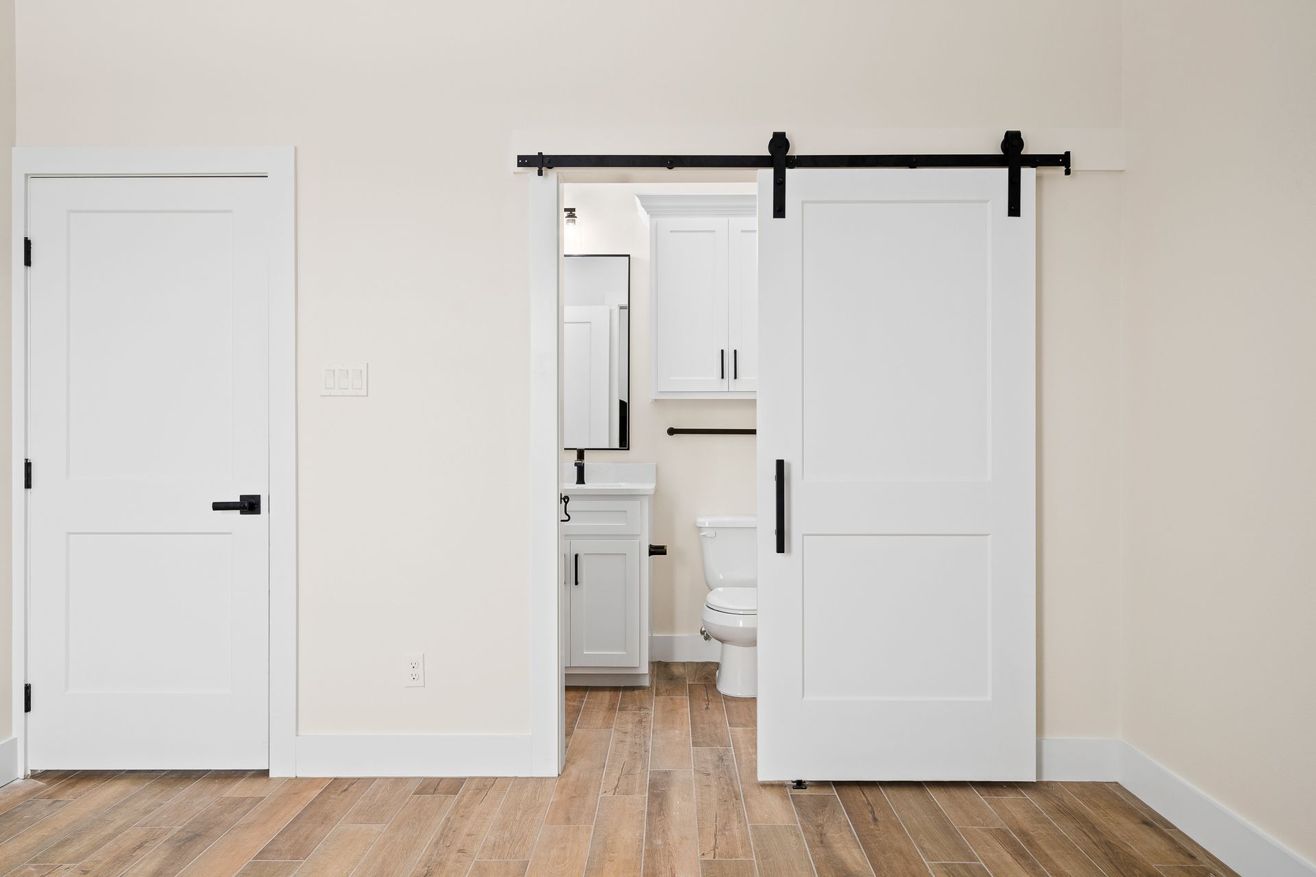 An empty room with a sliding barn door leading to a bathroom.