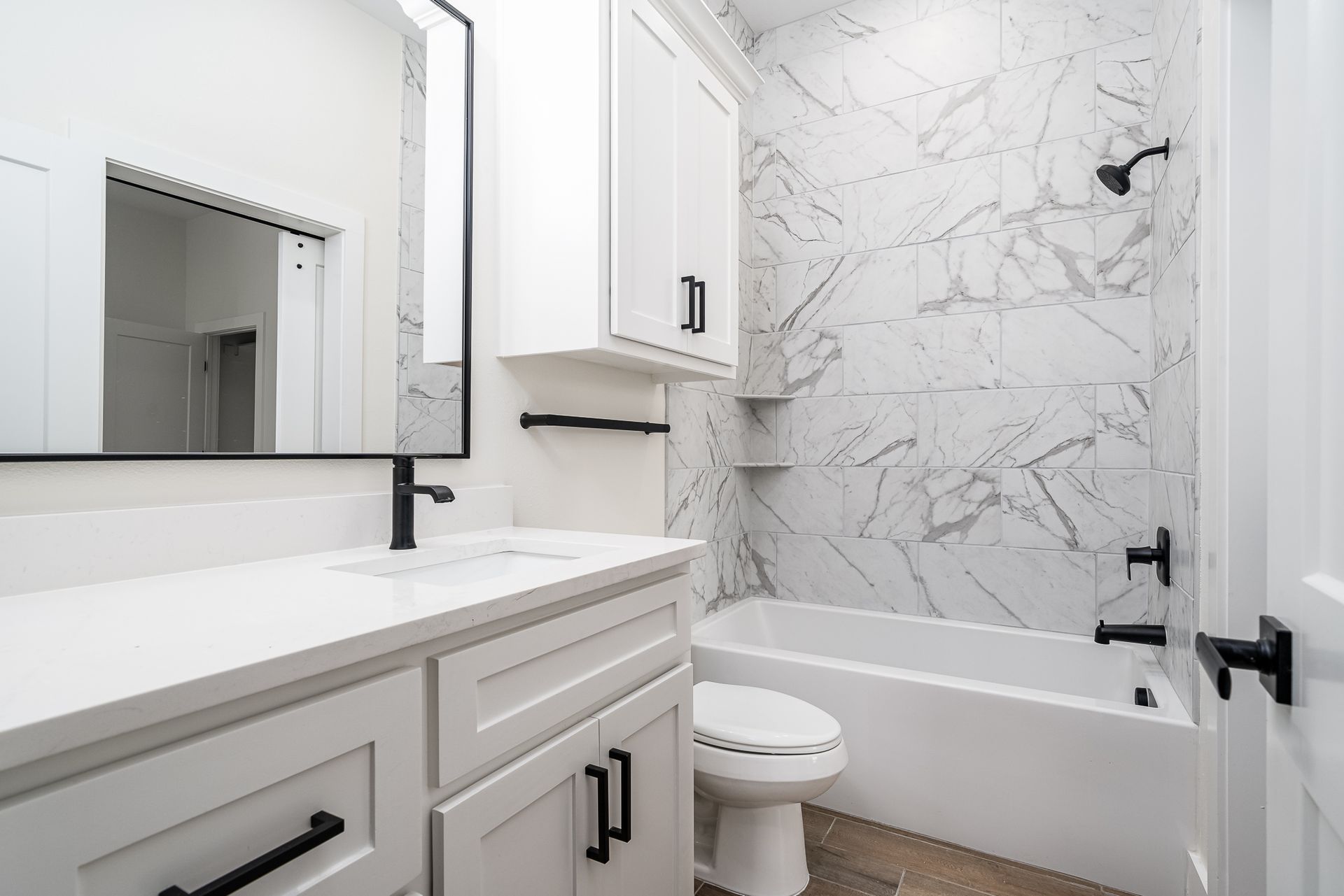 A bathroom with a toilet , sink , tub and mirror.