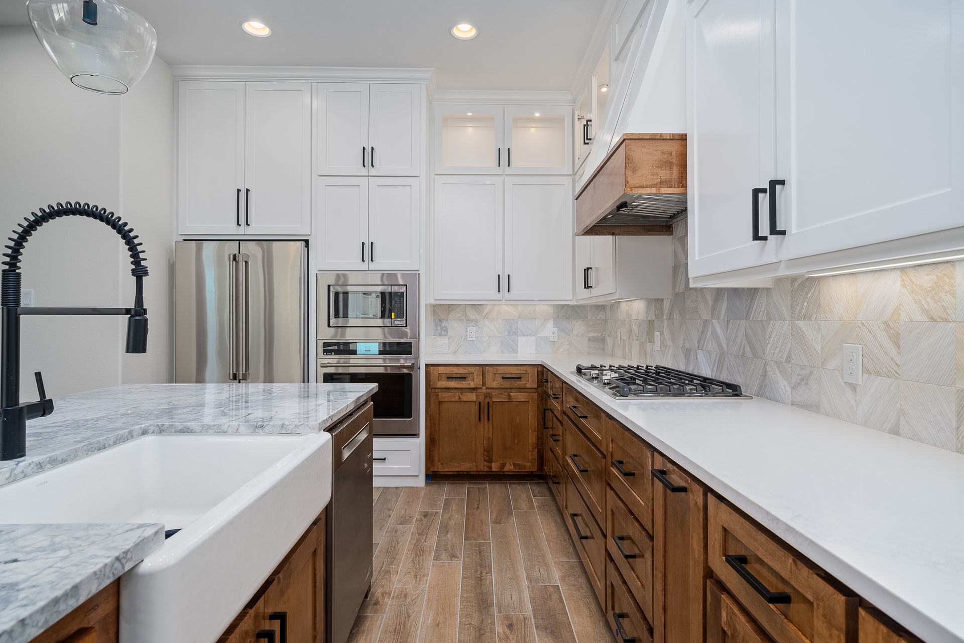 A kitchen with white cabinets , wooden cabinets , granite counter tops , stainless steel appliances and a sink.